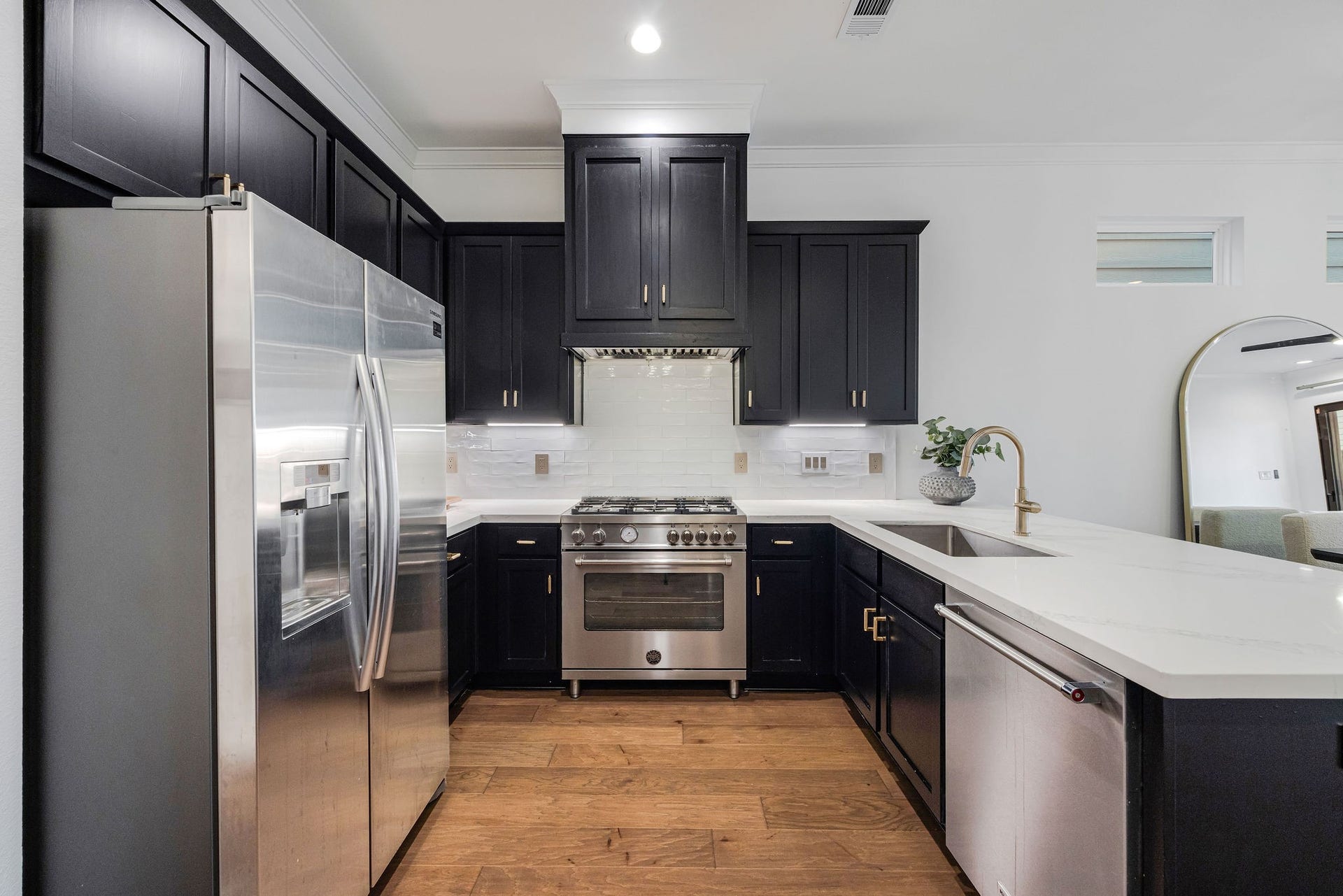 5537 Petty Street, Houston, TX 77007 Sleek modern kitchen featuring dark cabinetry, stainless steel appliances, and elegant quartz countertops, complemented by a stylish tile backsplash.