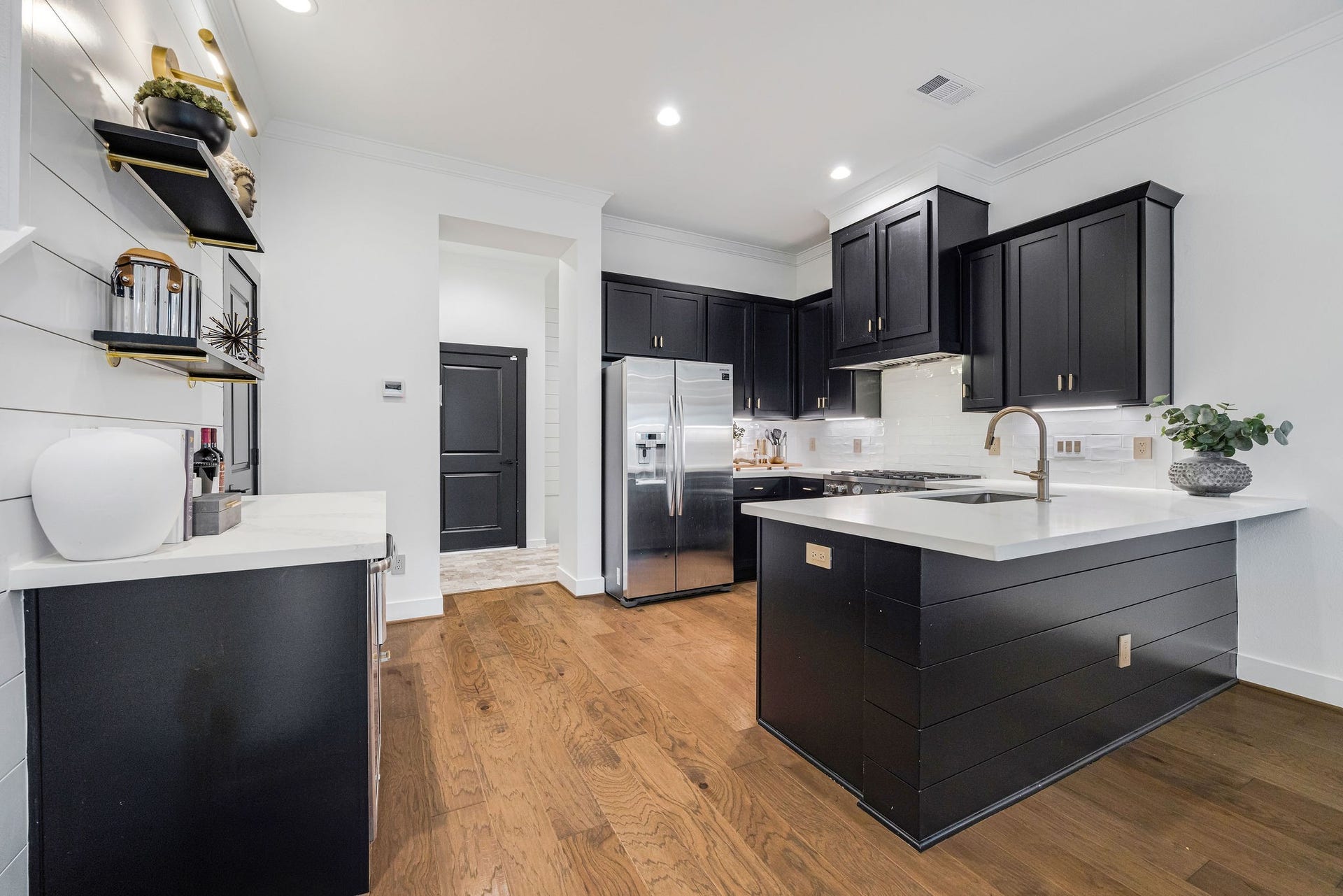 5537 Petty Street, Houston, TX 77007 Modern kitchen with sleek black cabinetry, stainless steel appliances, and a stylish island featuring a white countertop and elegant fixtures.