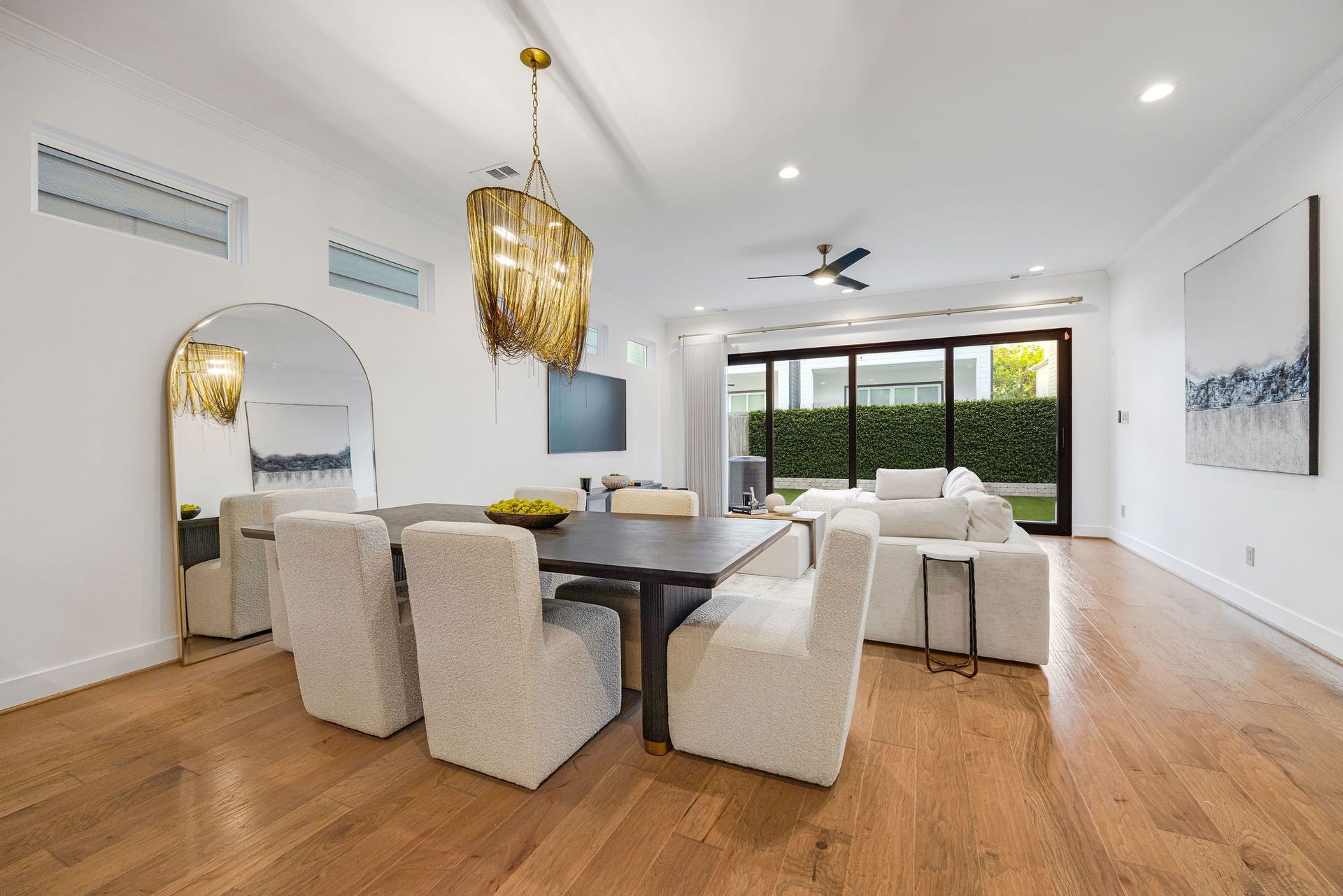 5537 Petty Street, Houston, TX 77007 Elegant open-concept living and dining area features sleek hardwood floors, a stylish chandelier, and large sliding doors leading to a lush outdoor space.