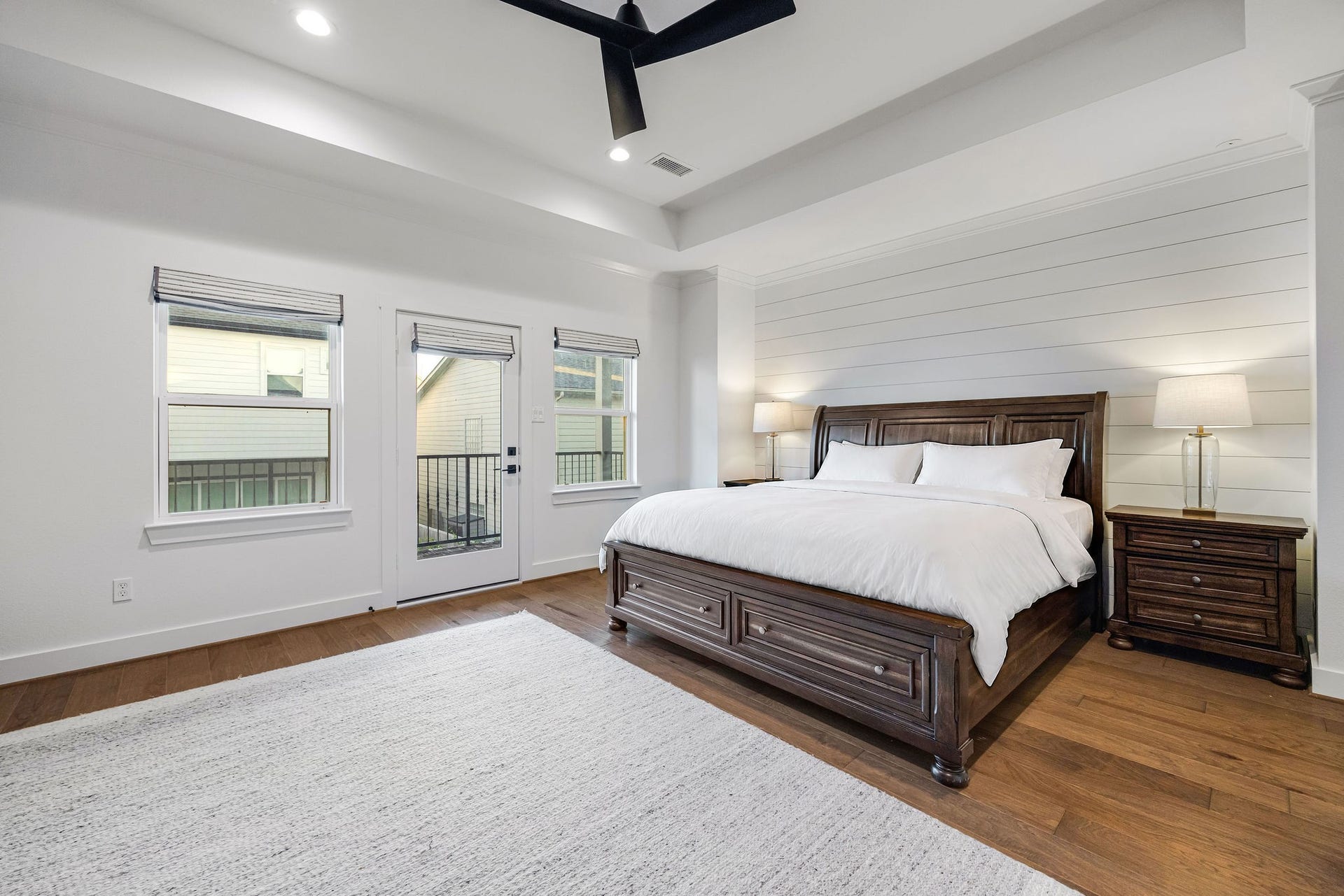 5537 Petty Street, Houston, TX 77007 Spacious primary bedroom featuring elegant shiplap accent wall, and abundant natural light from large windows and a glass door.