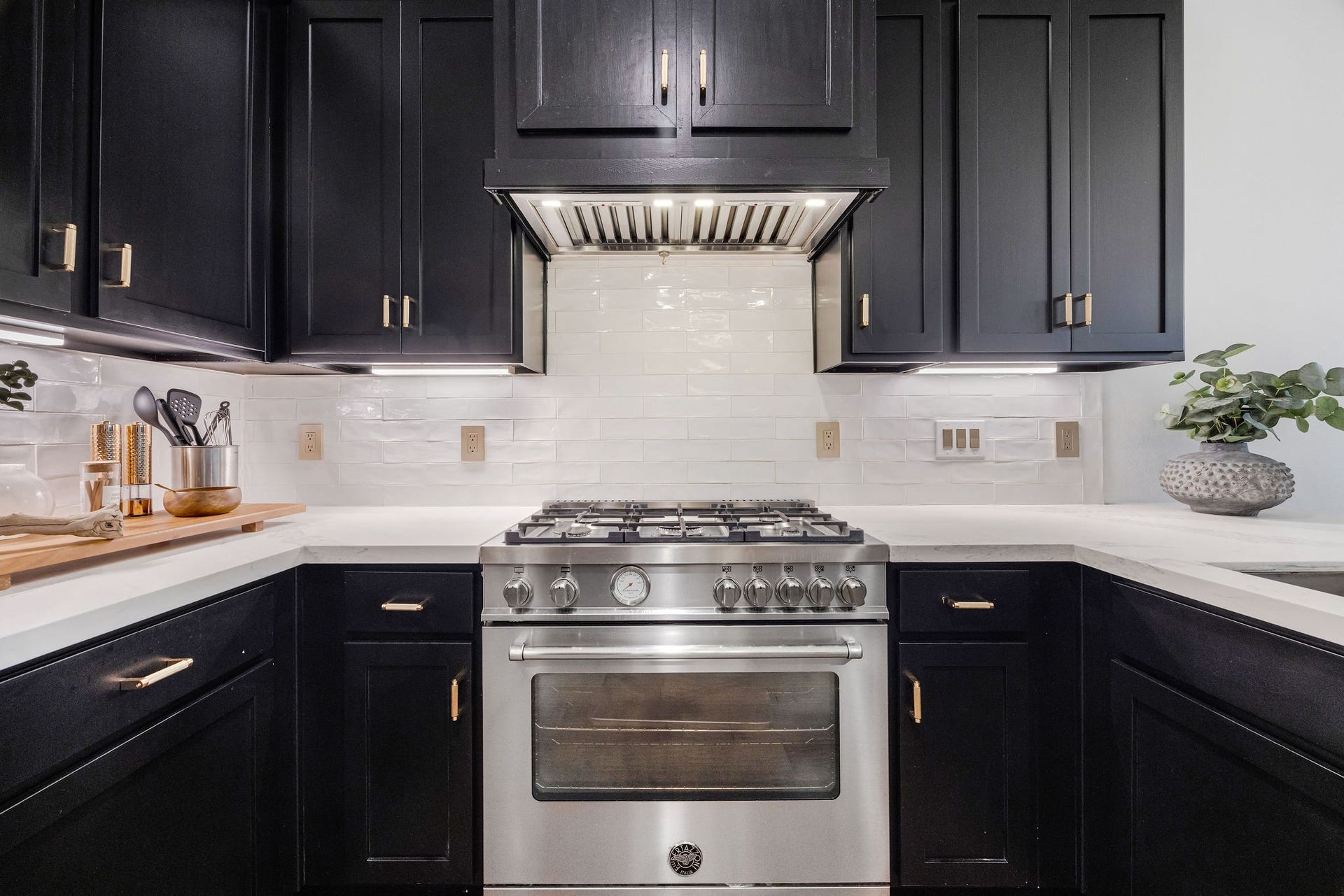 5537 Petty Street, Houston, TX 77007 Modern kitchen with sleek black cabinetry, stainless steel gas range, and elegant white subway tile backsplash.