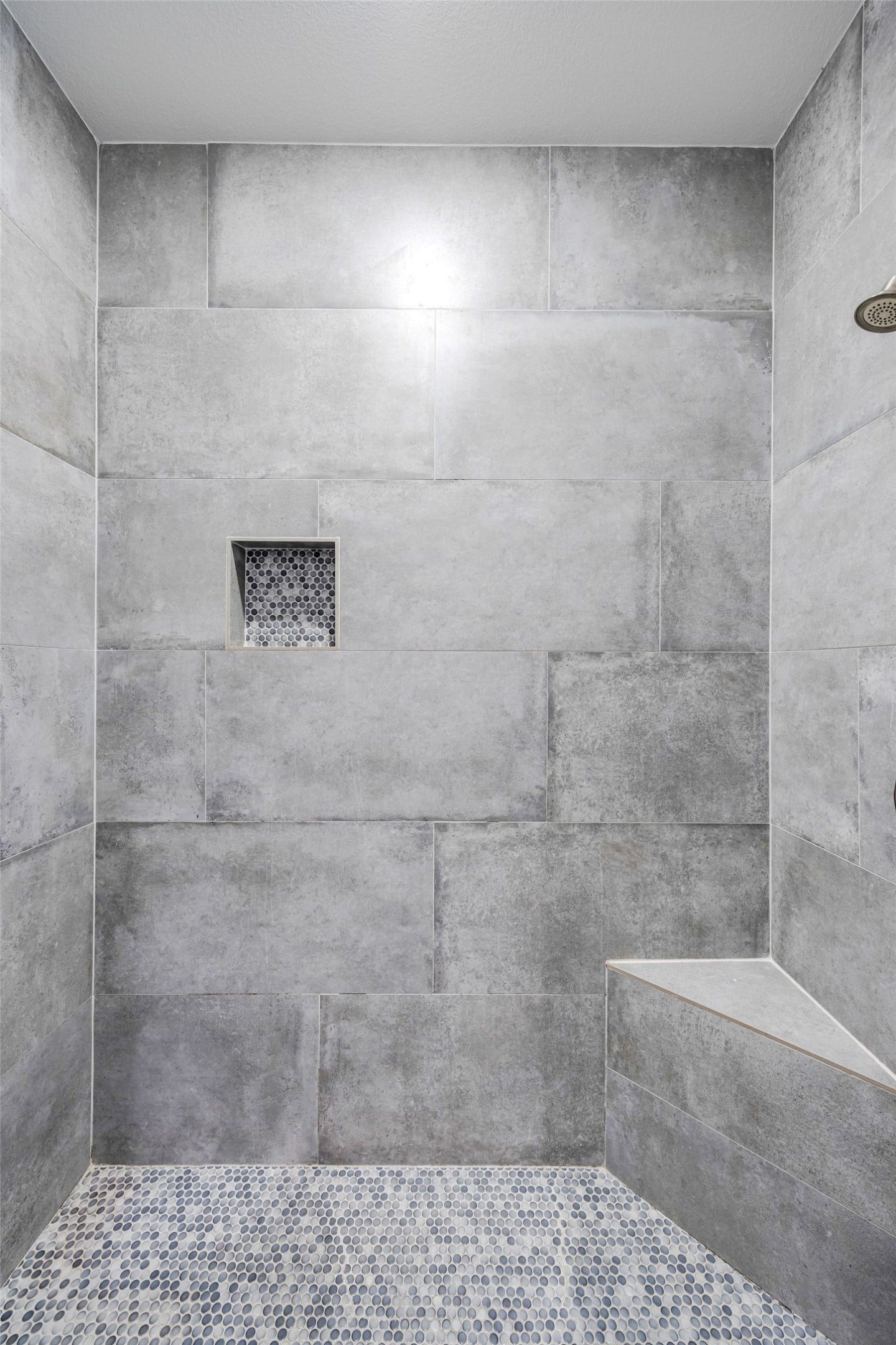 5537 Petty Street, Houston, TX 77007 Sleek and modern shower with gray tile, built-in niche, and a stylish pebble floor for a spa-like experience.