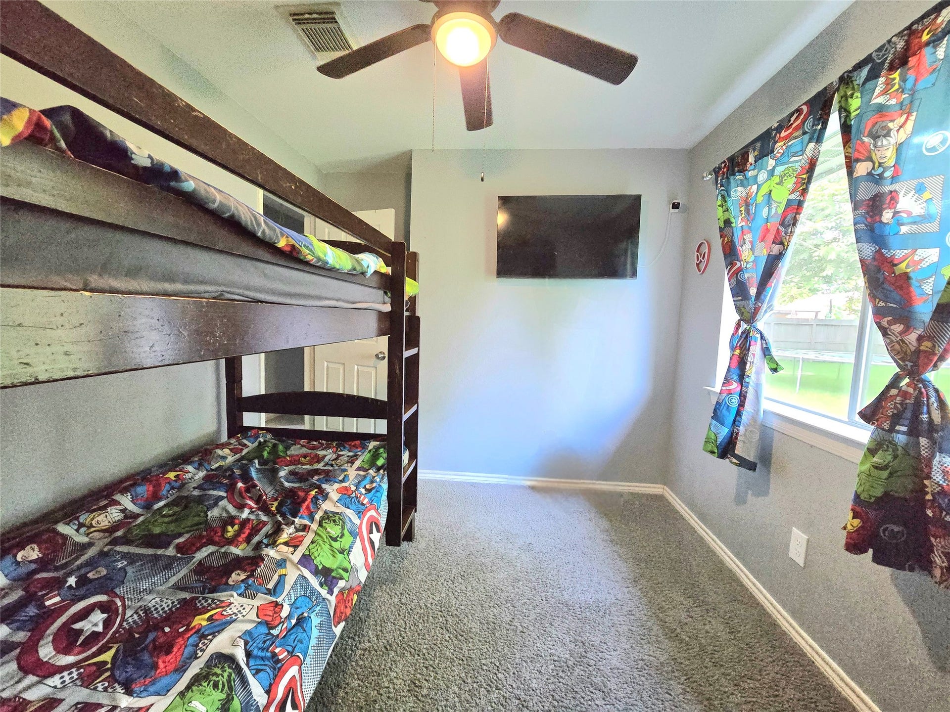 5205 Winding Brook Drive, Dickinson, TX 77539 Charming bedroom with cozy bunk beds, vibrant superhero-themed decor, and a large window providing ample natural light.