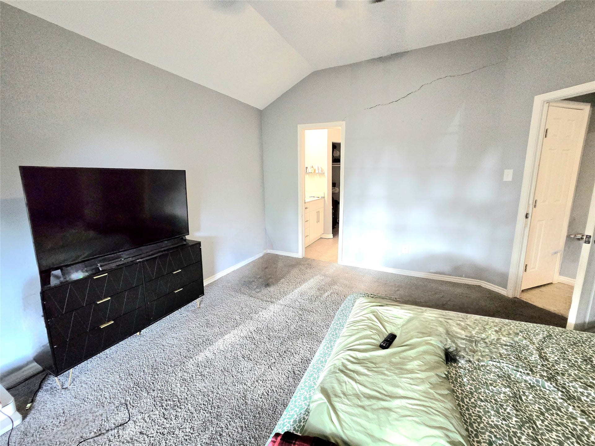5205 Winding Brook Drive, Dickinson, TX 77539 Spacious bedroom with vaulted ceilings, neutral tones, and an ensuite bathroom for added convenience.
