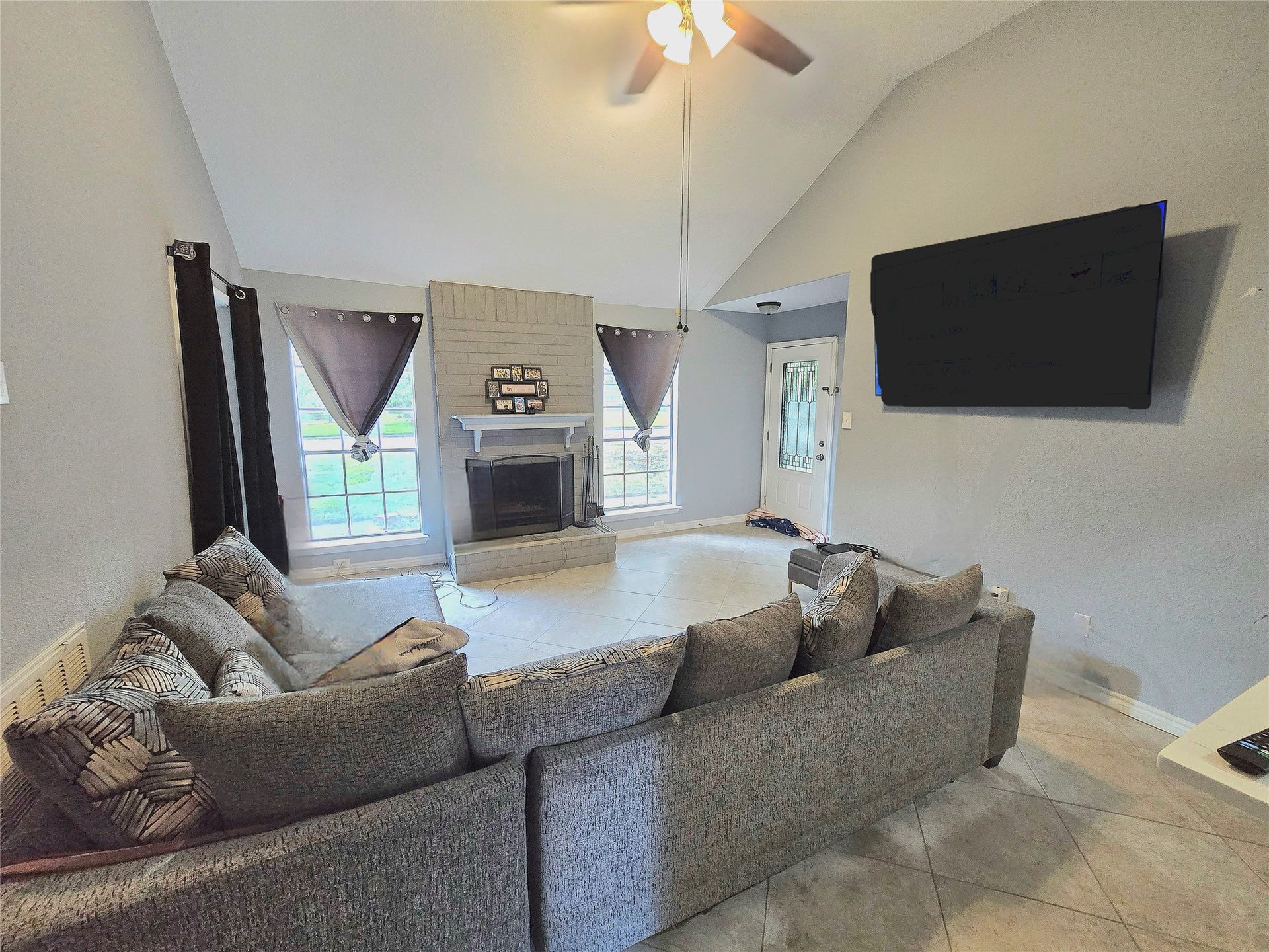 5205 Winding Brook Drive, Dickinson, TX 77539 Spacious living room featuring a cozy fireplace, large windows for natural light, and a modern ceiling fan.