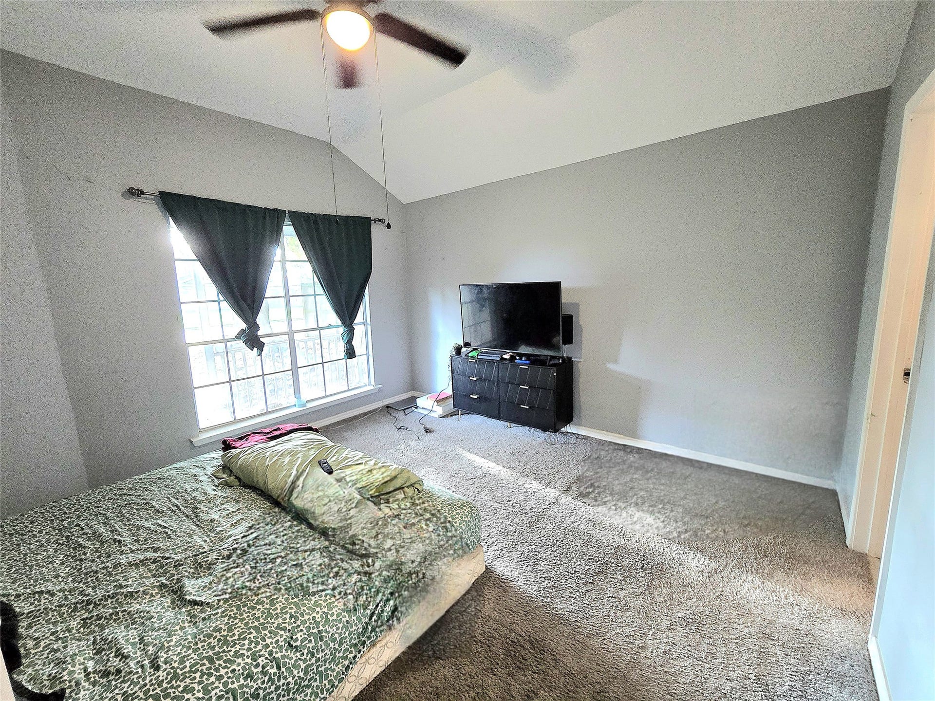 5205 Winding Brook Drive, Dickinson, TX 77539 Spacious bedroom with vaulted ceilings, large window for natural light, and a ceiling fan for comfort.