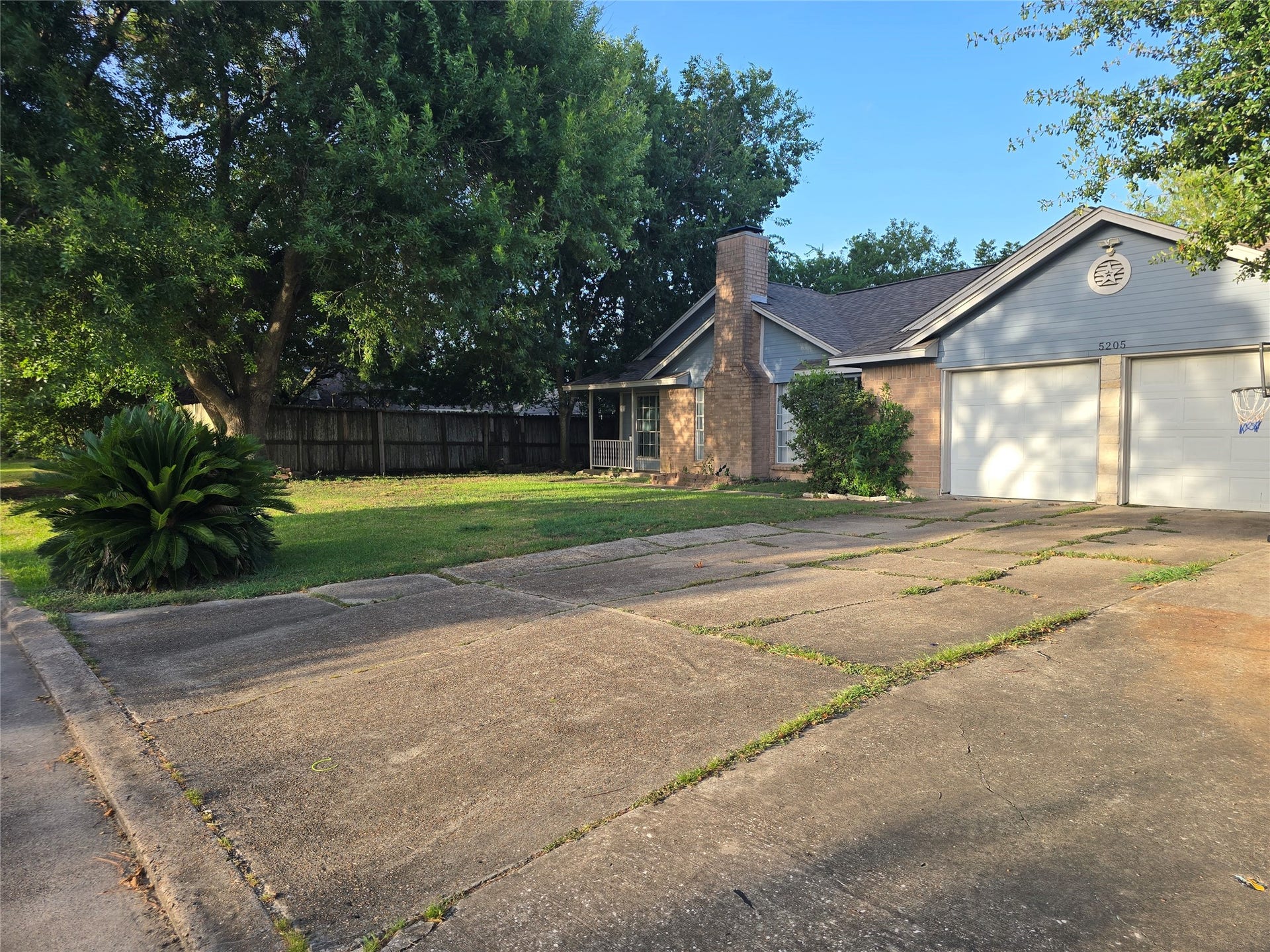 5205 Winding Brook Drive, Dickinson, TX 77539 Charming single-story home with a spacious driveway, attached garage, and a lush front yard accented by mature trees and well-kept landscaping.