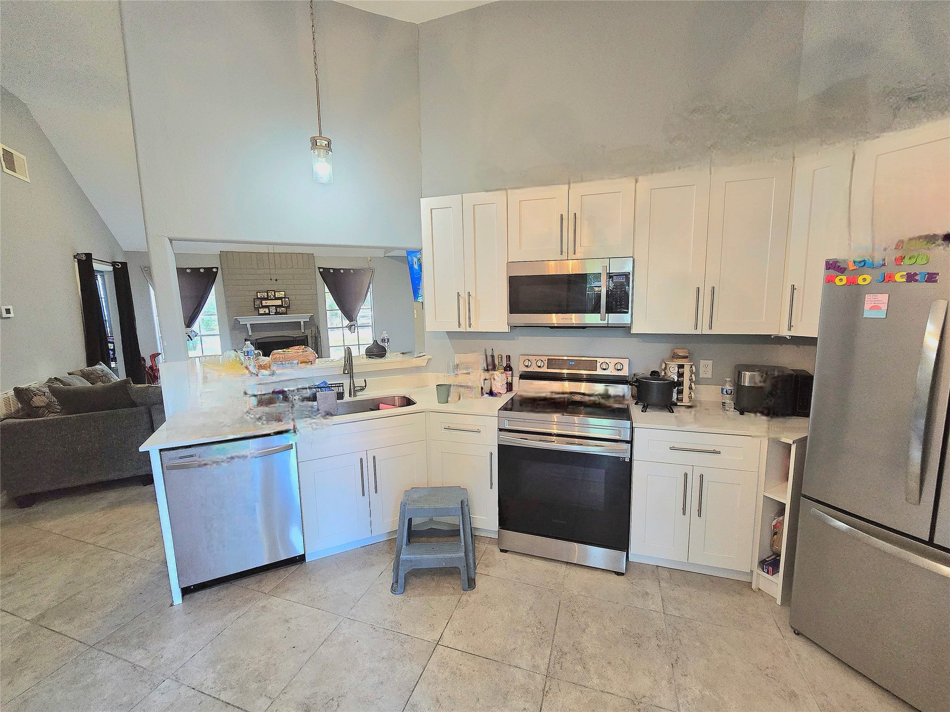 5205 Winding Brook Drive, Dickinson, TX 77539 Modern kitchen with sleek stainless steel appliances, white cabinetry, and open access to a cozy living area featuring a fireplace.