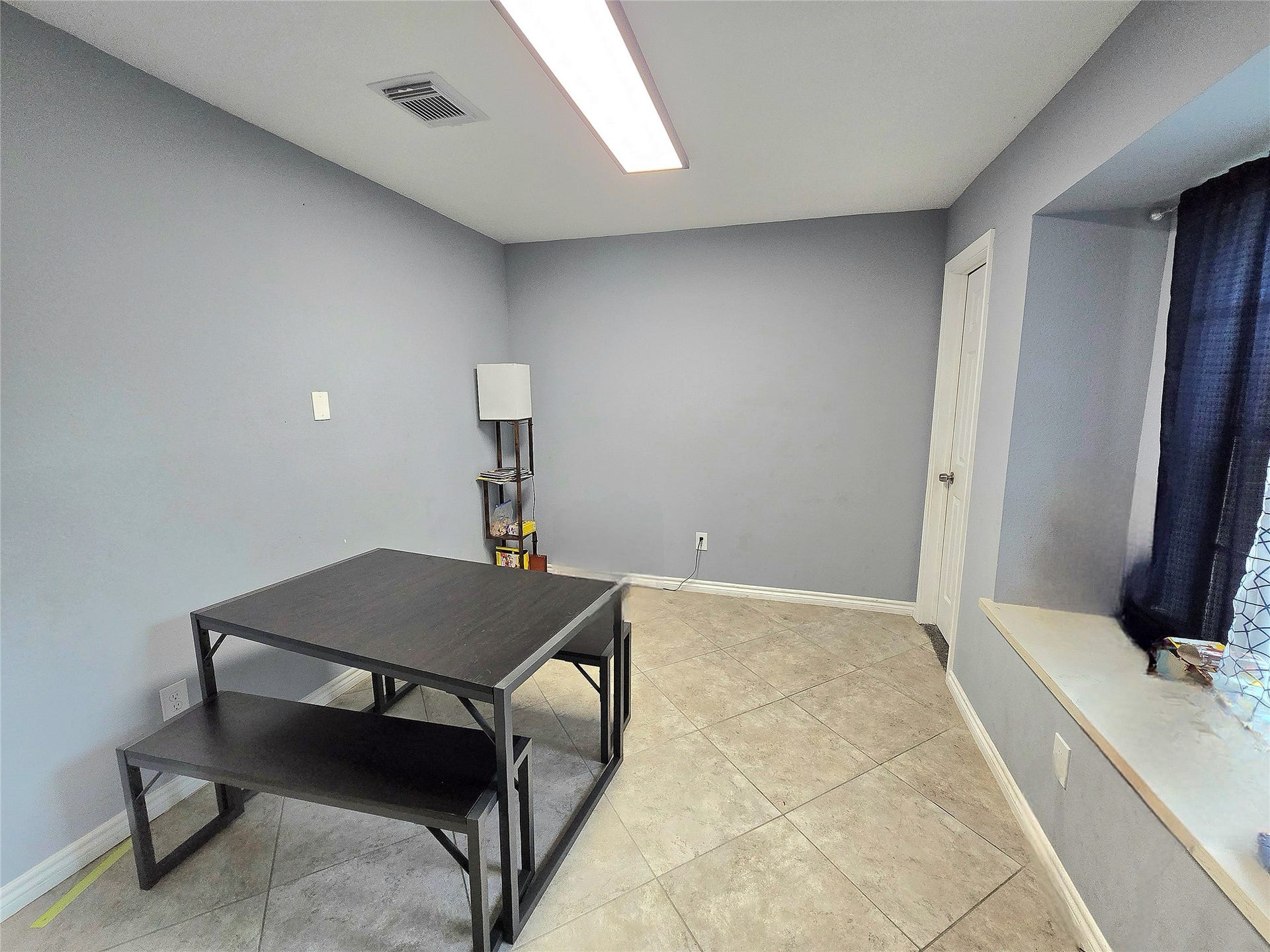 5205 Winding Brook Drive, Dickinson, TX 77539 Bright and versatile room featuring neutral tile flooring, soft gray walls, and ample natural light from a large window, perfect for a dining or workspace.