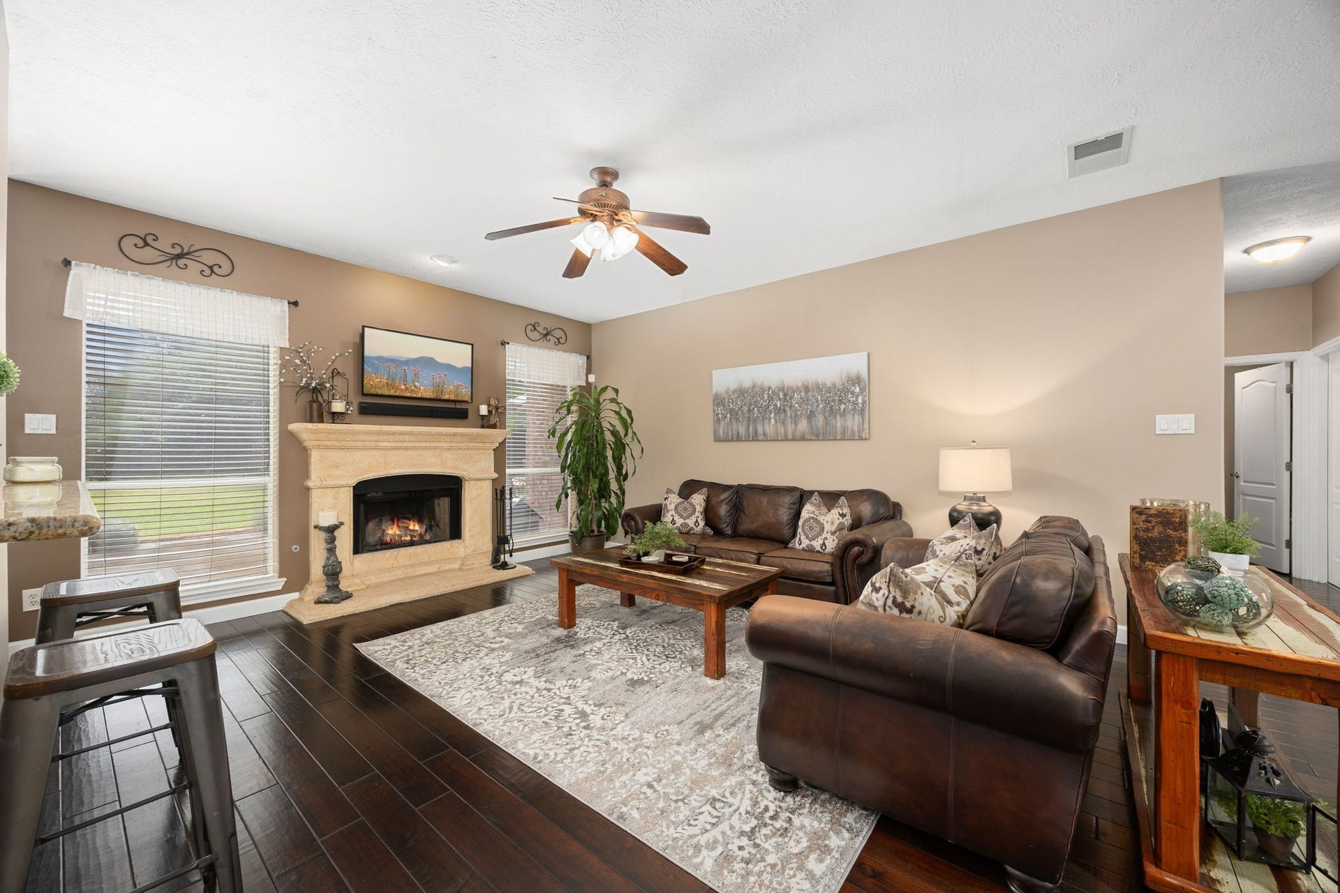 1427 Queens Bay Drive, Katy, TX 77494 The family room invites you in with a cozy gas fireplace framed by a stone surround, updated hardwood flooring, and 2 large windows, the perfect space for relaxing or entertaining.