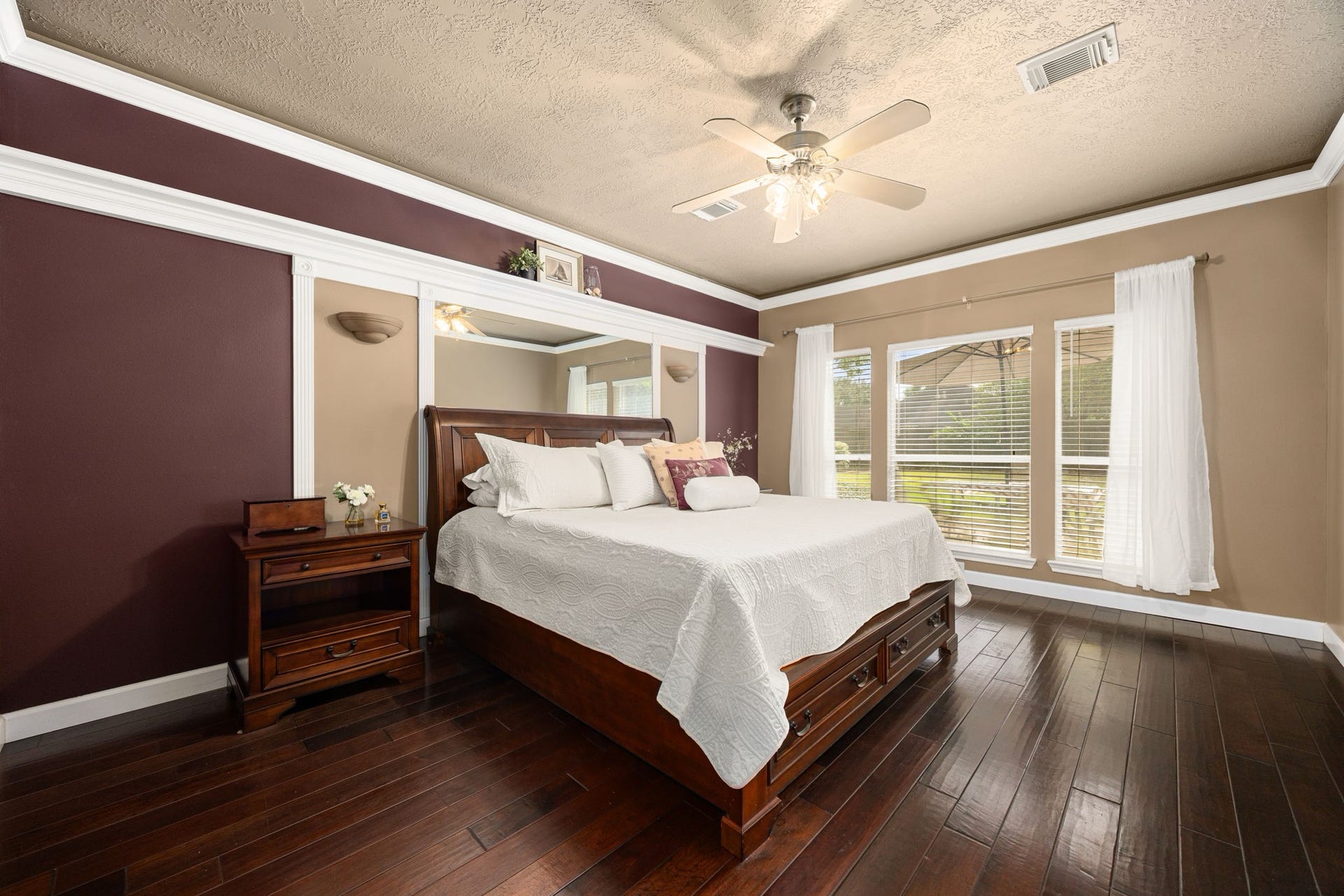 1427 Queens Bay Drive, Katy, TX 77494 The first-floor primary bedroom offers beautiful wood flooring, crown molding, a ceiling fan, and large windows framing serene views of the backyard.