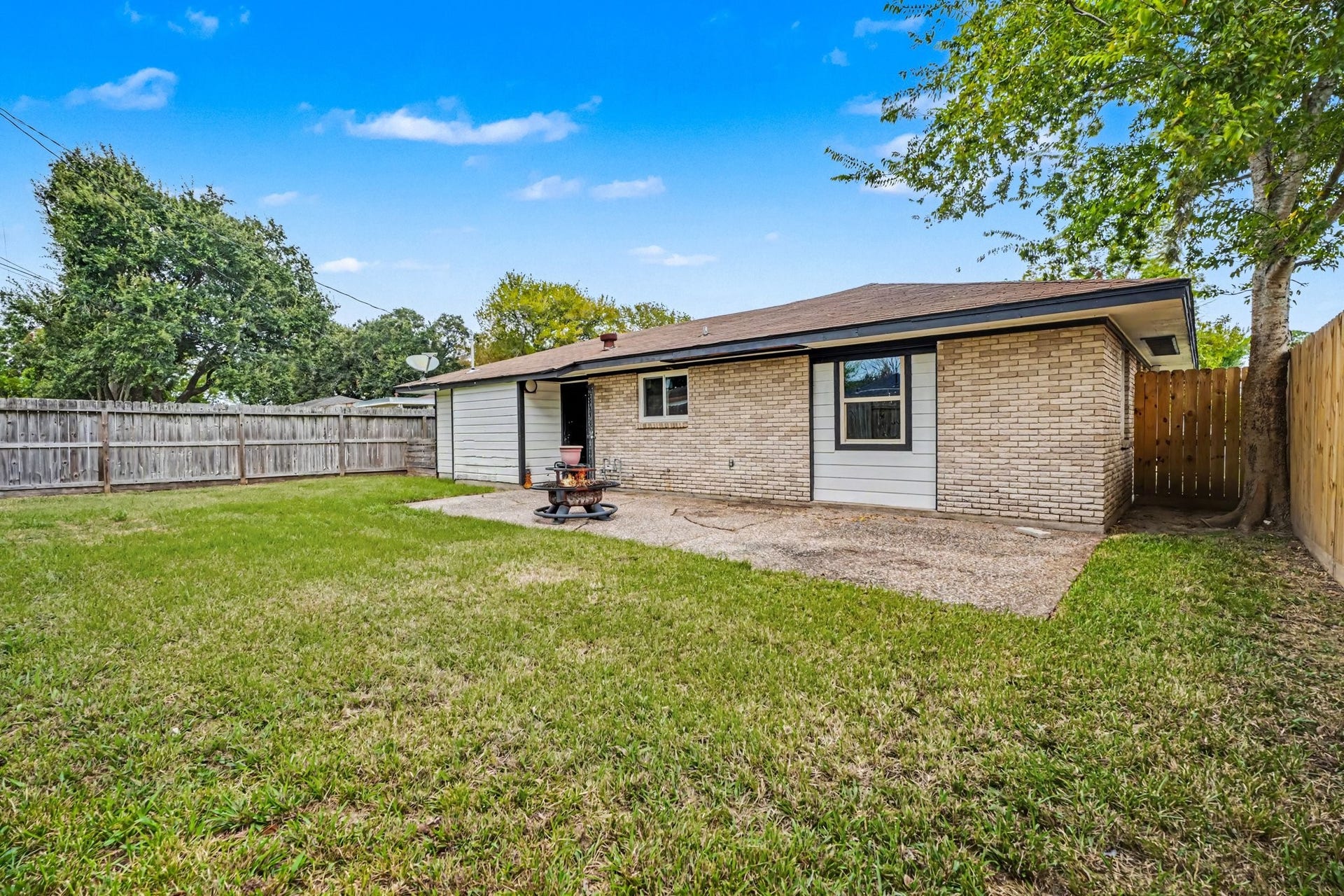 1317 N Natchez Drive, Texas City, TX 77591 Charming backyard with a spacious lawn, perfect for outdoor activities, bordered by a wooden fence for privacy.