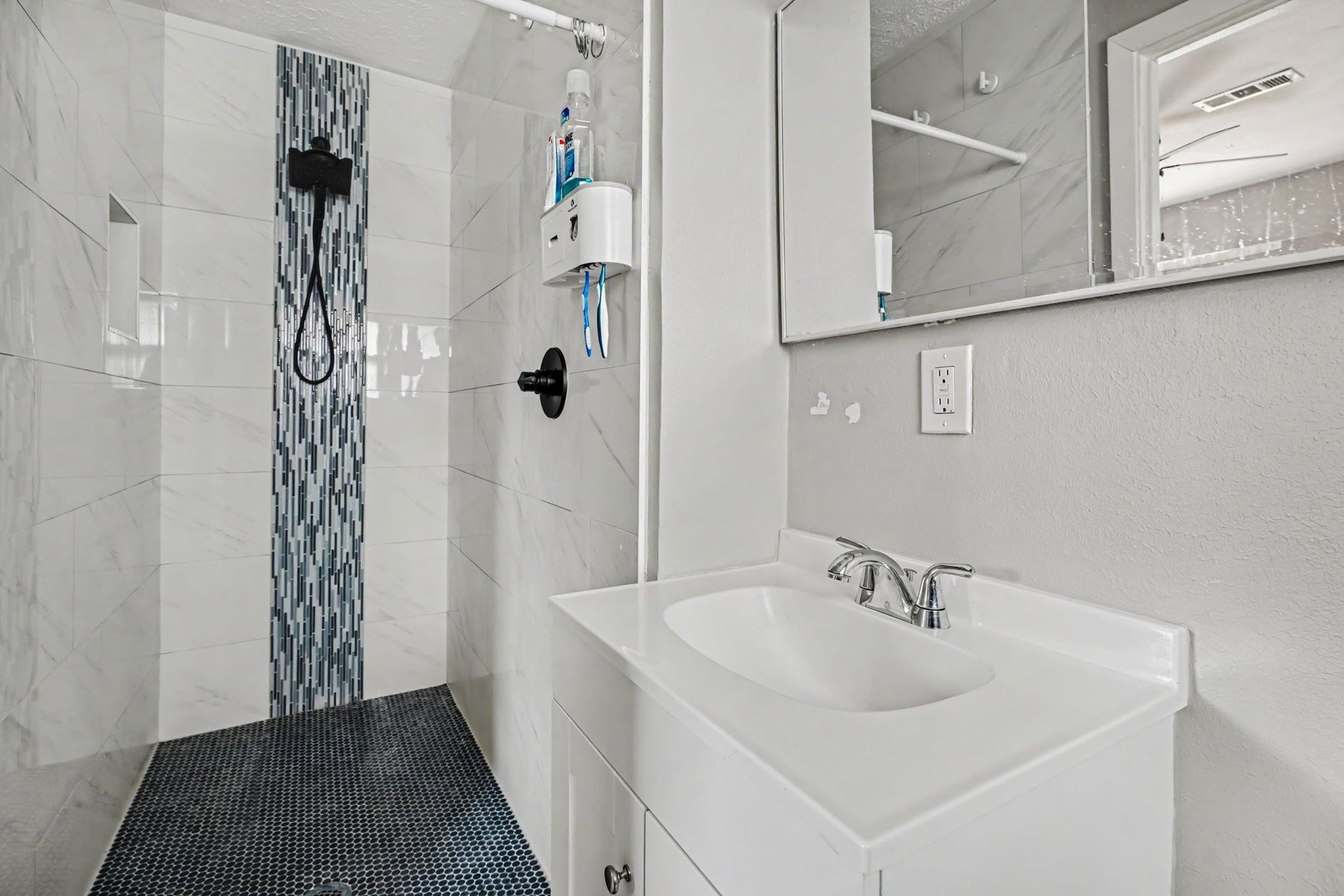 1317 N Natchez Drive, Texas City, TX 77591 Primary Modern bathroom featuring a sleek walk-in shower with stylish vertical mosaic accents and a chic white vanity with a contemporary faucet.