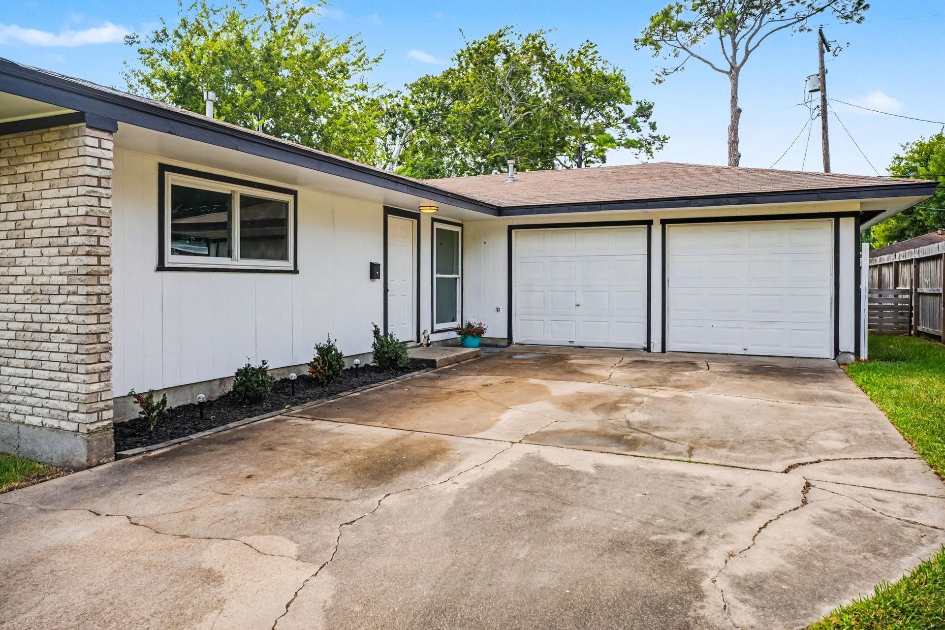 1317 N Natchez Drive, Texas City, TX 77591 Charming home with a welcoming driveway leading to a spacious two-car garage. The exterior features classic white brick and siding, complemented by neat landscaping.