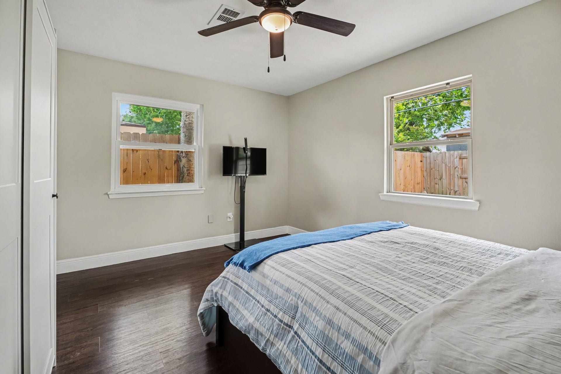 1317 N Natchez Drive, Texas City, TX 77591 Primary bedroom featuring hardwood floors, ample natural light from two windows, and a ceiling fan for comfort.