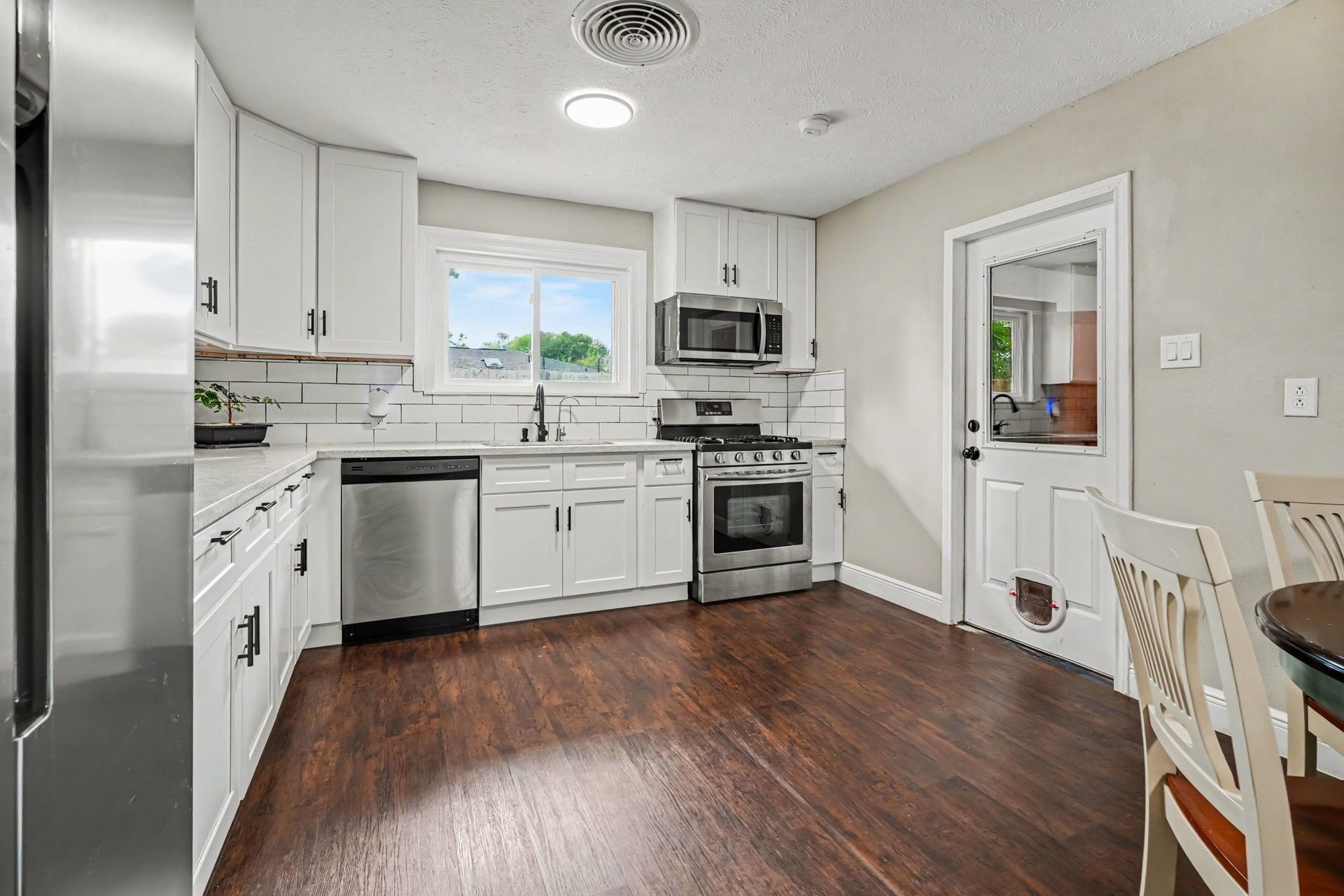 1317 N Natchez Drive, Texas City, TX 77591 Bright and modern kitchen with sleek stainless steel appliances, elegant white cabinetry, and rich laminate flooring, offering a perfect blend of style and functionality.