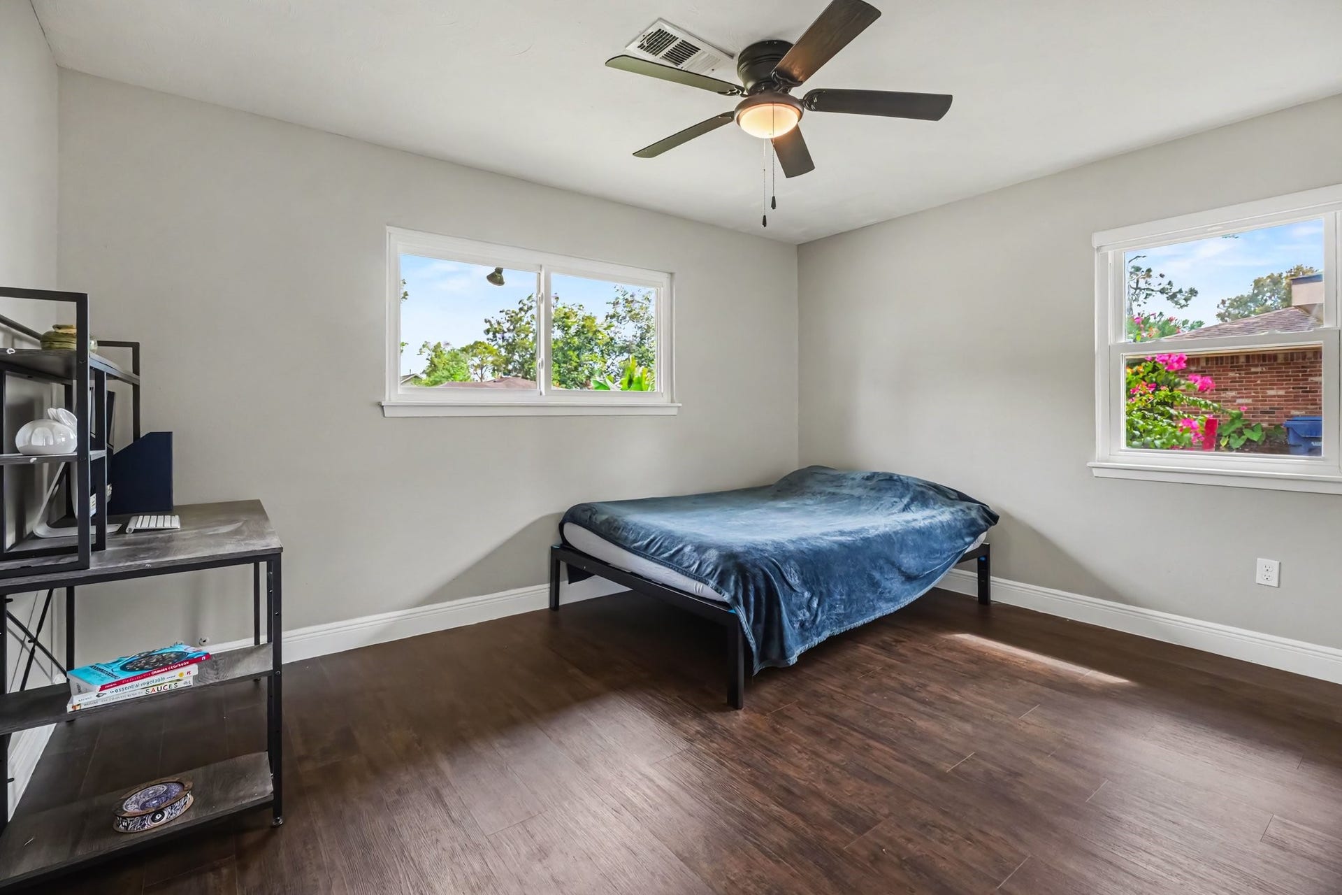 1317 N Natchez Drive, Texas City, TX 77591 Bedroom One with laminate floors, featuring a ceiling fan, ample natural light from two windows, and a spacious layout ideal for relaxation or work.