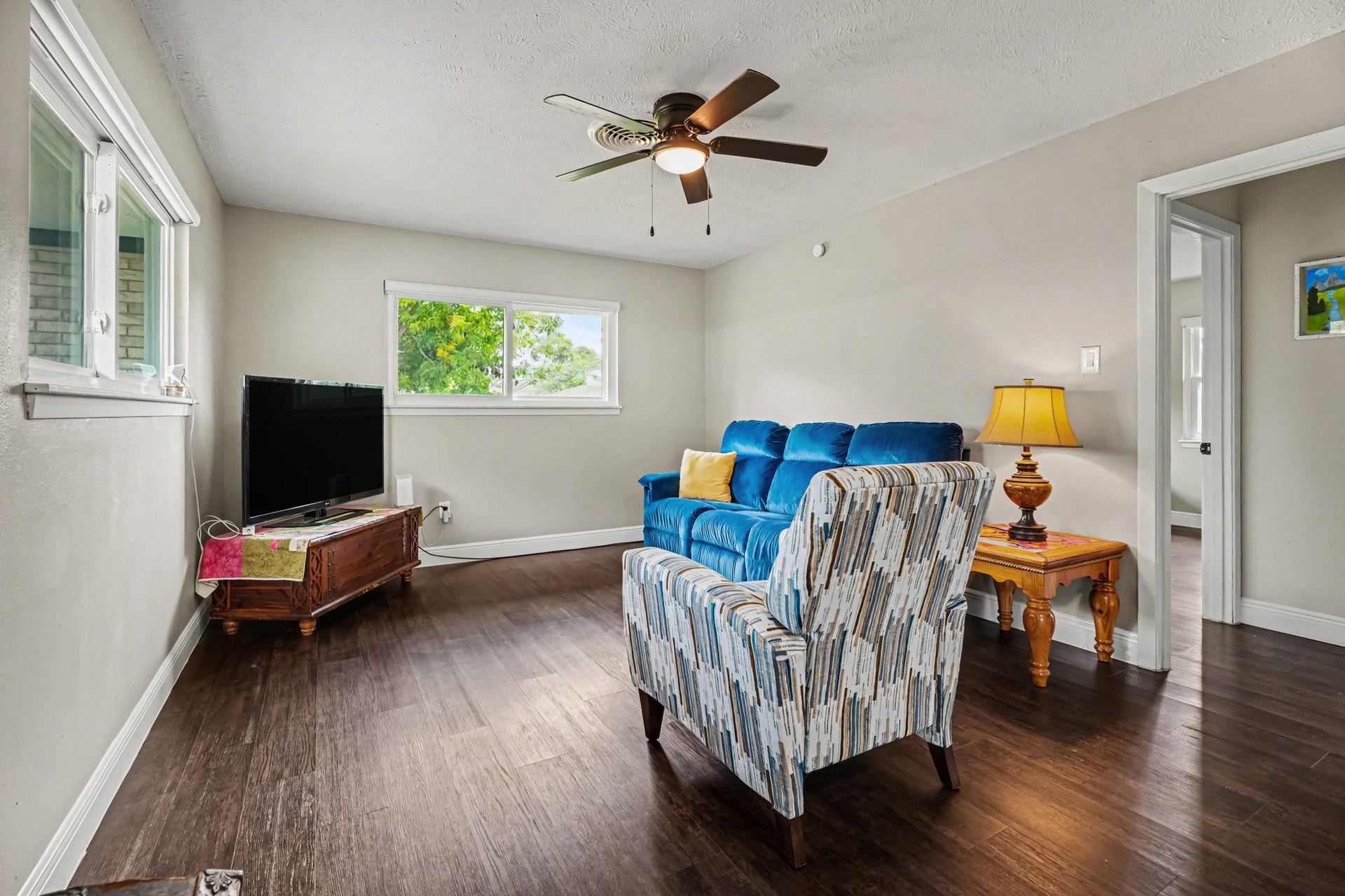 1317 N Natchez Drive, Texas City, TX 77591 Cozy living room featuring hardwood floors, a ceiling fan, and abundant natural light, perfect for relaxation and entertainment.