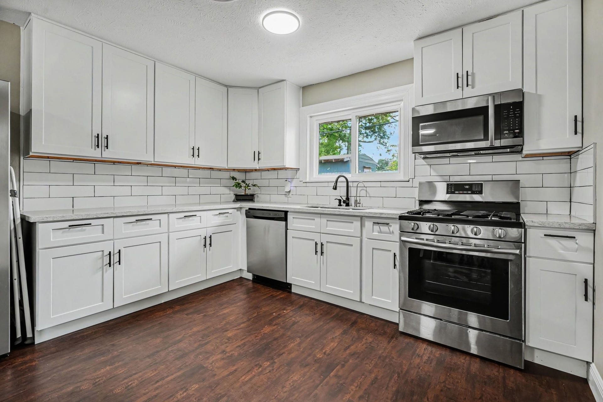 1317 N Natchez Drive, Texas City, TX 77591 Modern kitchen with sleek stainless steel appliances, subway tile backsplash, and elegant white cabinetry, complemented by laminate floors.