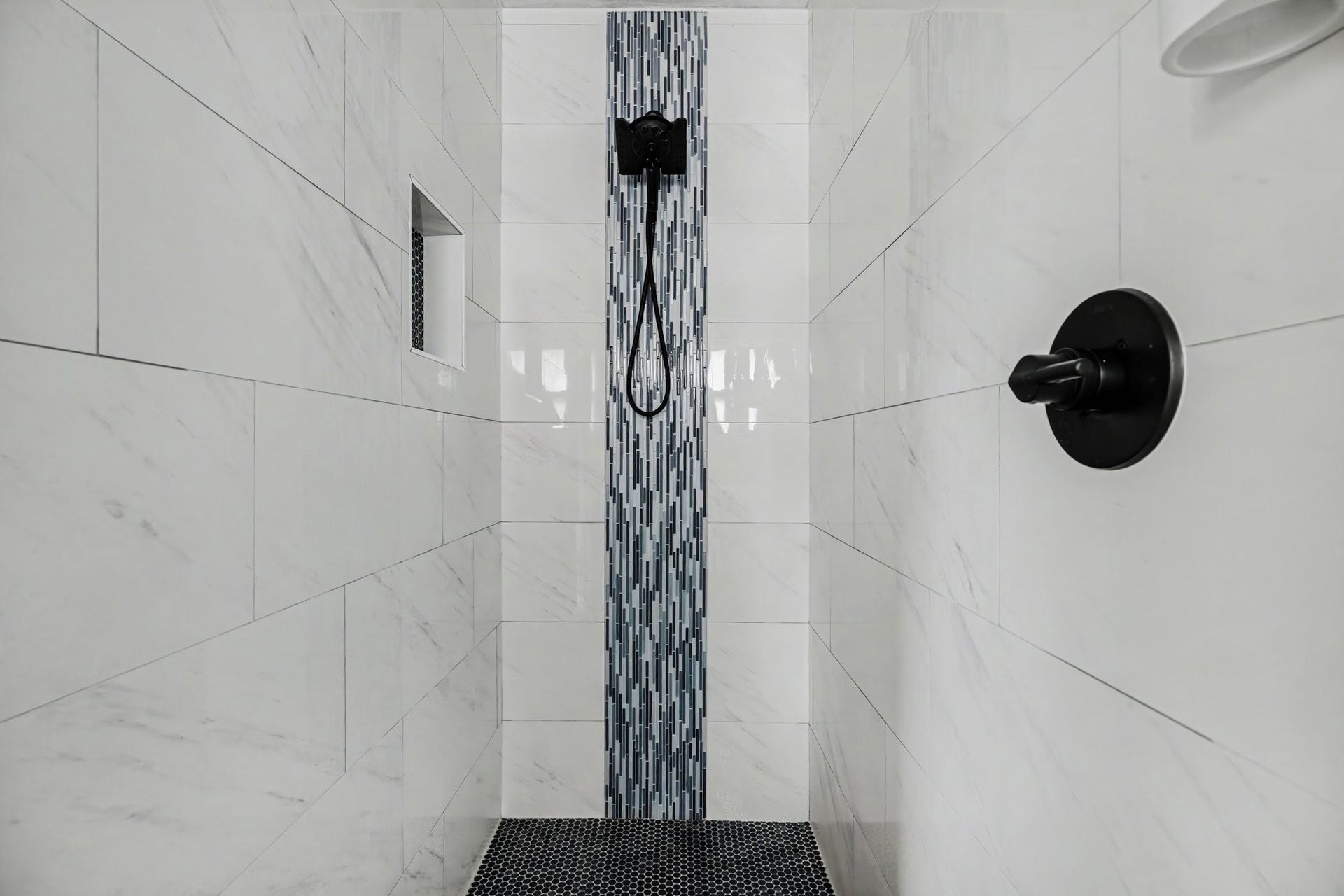 1317 N Natchez Drive, Texas City, TX 77591 Primary shower with sleek white tile, a striking vertical mosaic accent, and modern black fixtures for a luxurious touch.