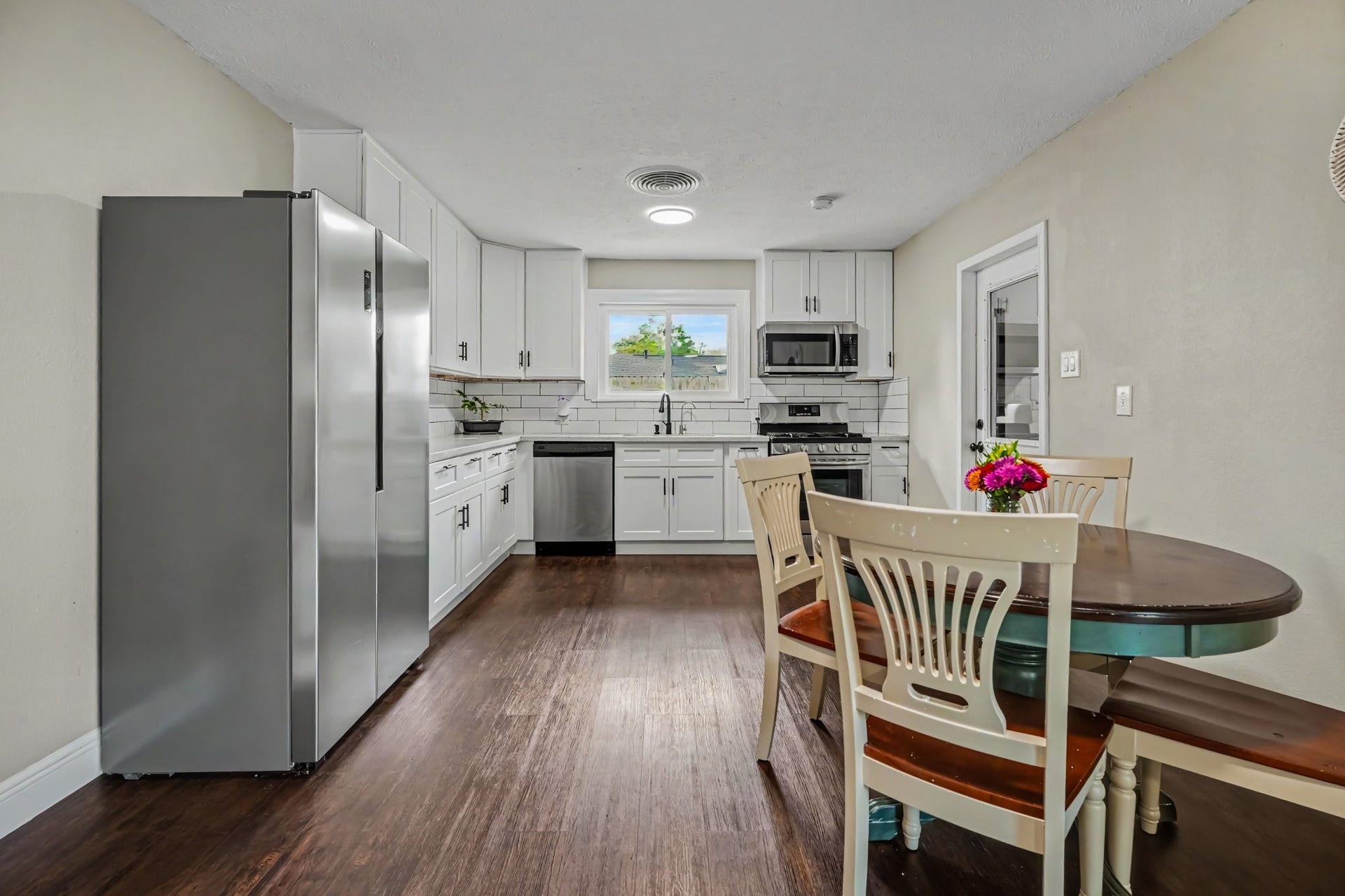 1317 N Natchez Drive, Texas City, TX 77591 Bright and spacious kitchen with modern stainless steel appliances, sleek white cabinetry, and laminate floors, complemented by a cozy dining area.