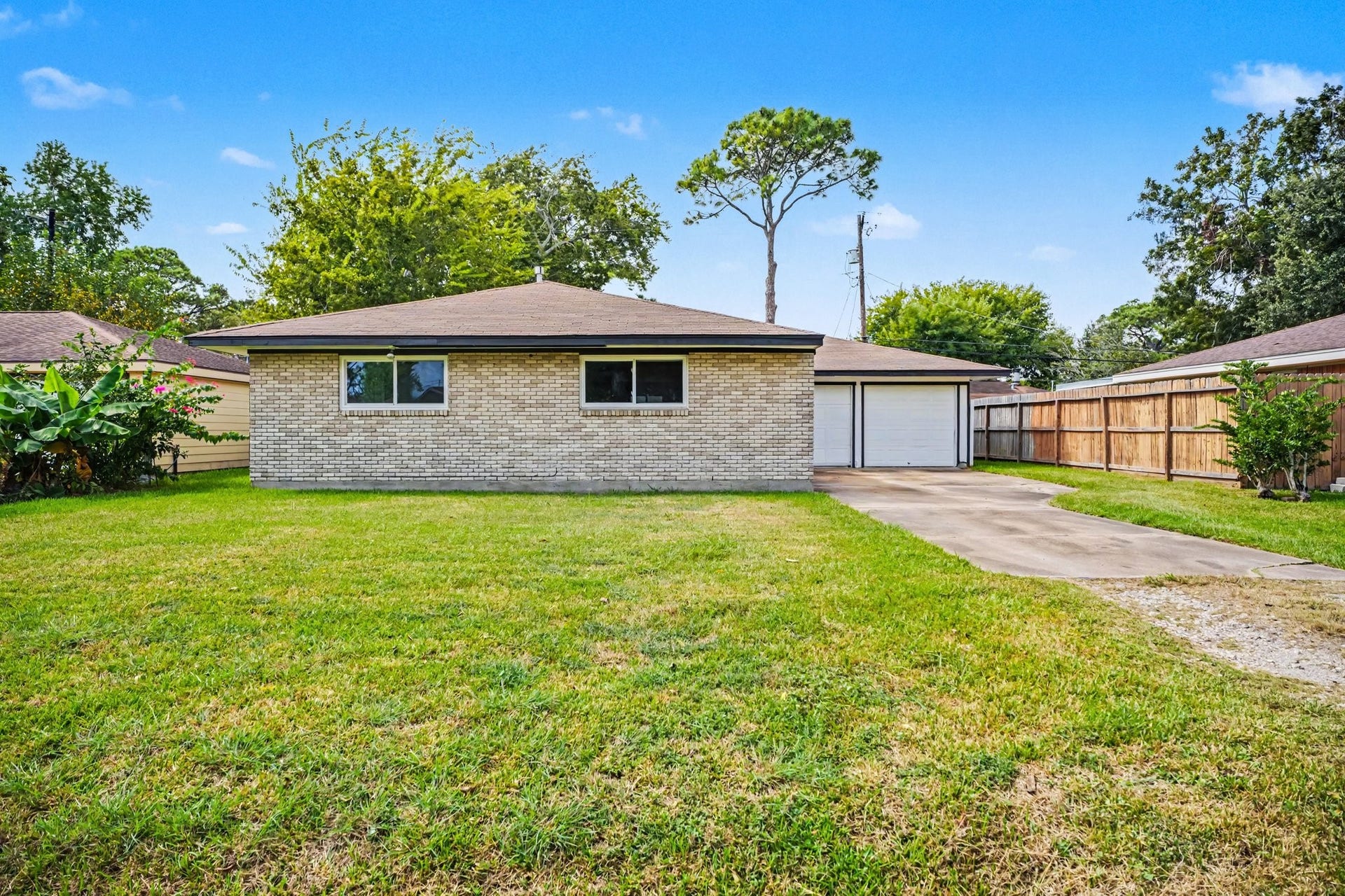 1317 N Natchez Drive, Texas City, TX 77591 Charming single-story brick home with a spacious front yard and a long driveway leading to a detached garage.