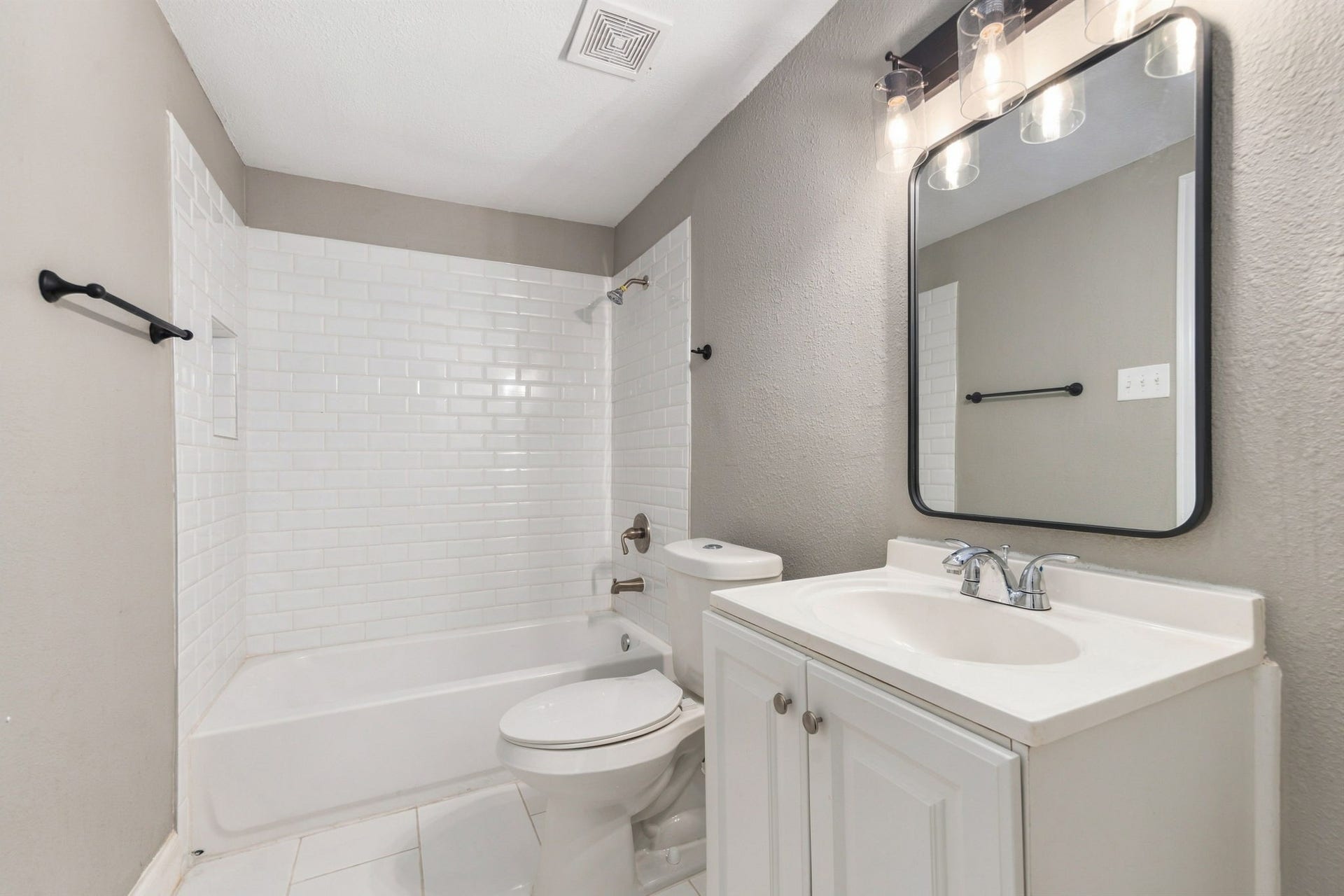 4637 Larkspur Street, Houston, TX 77051 Modern bathroom featuring a sleek vanity with a contemporary mirror, complemented by a classic white bathtub and subway tile surround for a stylish touch.