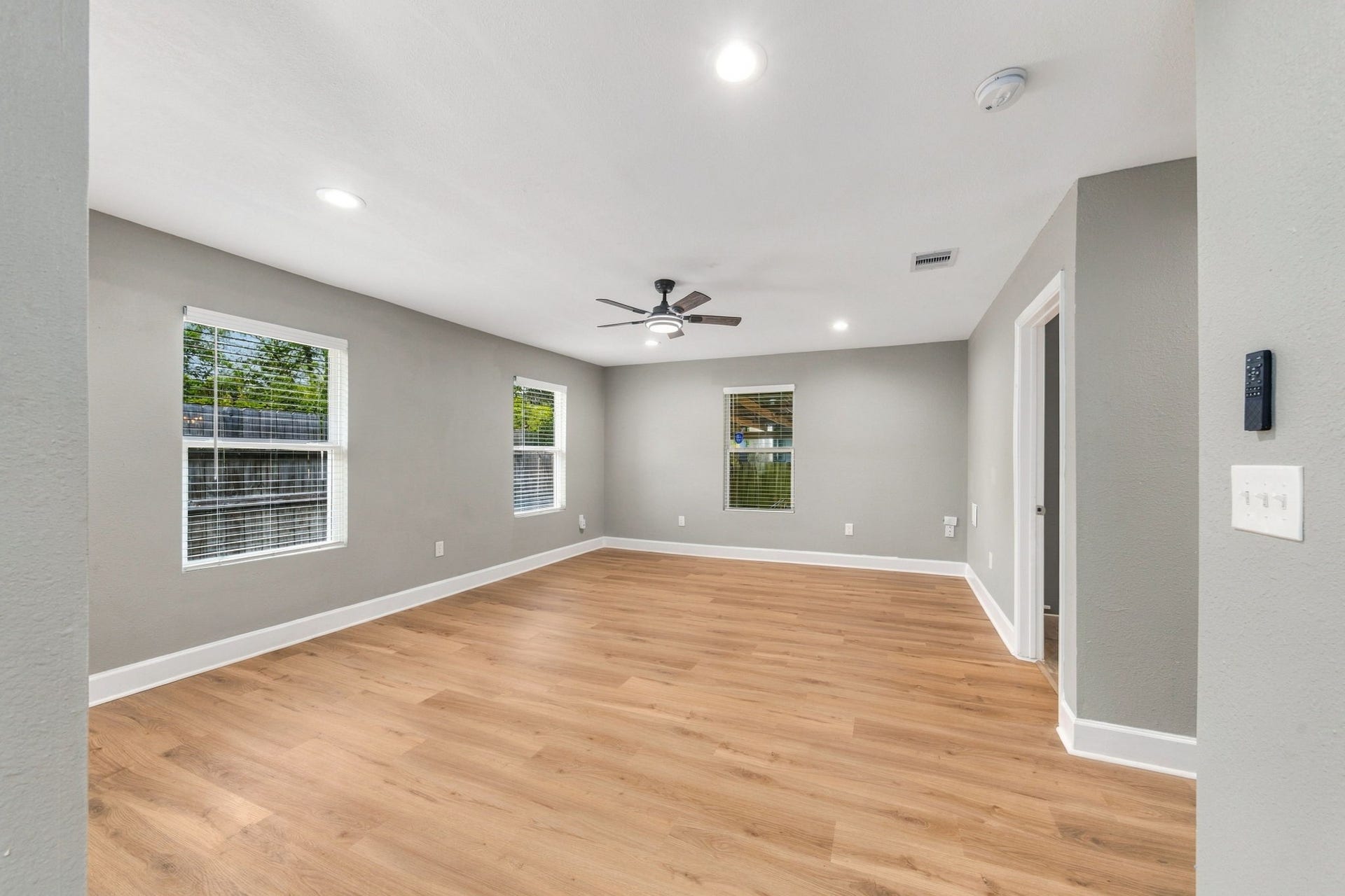 4637 Larkspur Street, Houston, TX 77051 Spacious living area featuring sleek hardwood floors, modern gray walls, and ample natural light from multiple windows.
