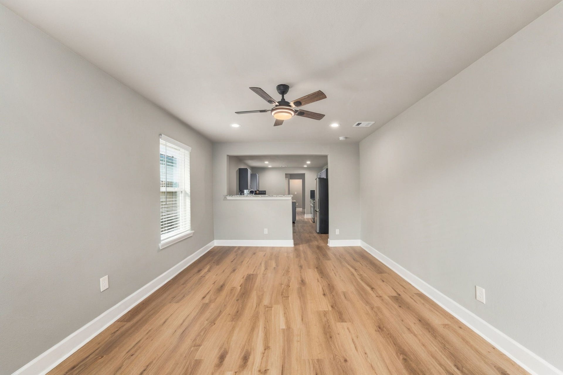 4637 Larkspur Street, Houston, TX 77051 Spacious living area with elegant wood flooring, modern ceiling fan, and ample natural light, seamlessly connecting to the kitchen for an open-concept feel.