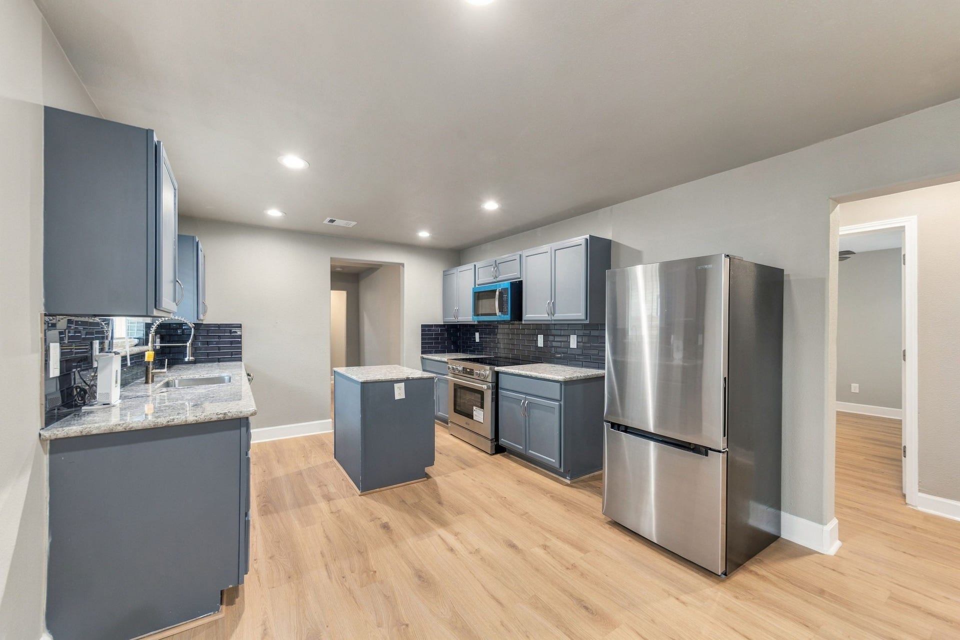 4637 Larkspur Street, Houston, TX 77051 Modern kitchen featuring sleek stainless steel appliances, elegant gray cabinetry, and a stylish dark backsplash.
