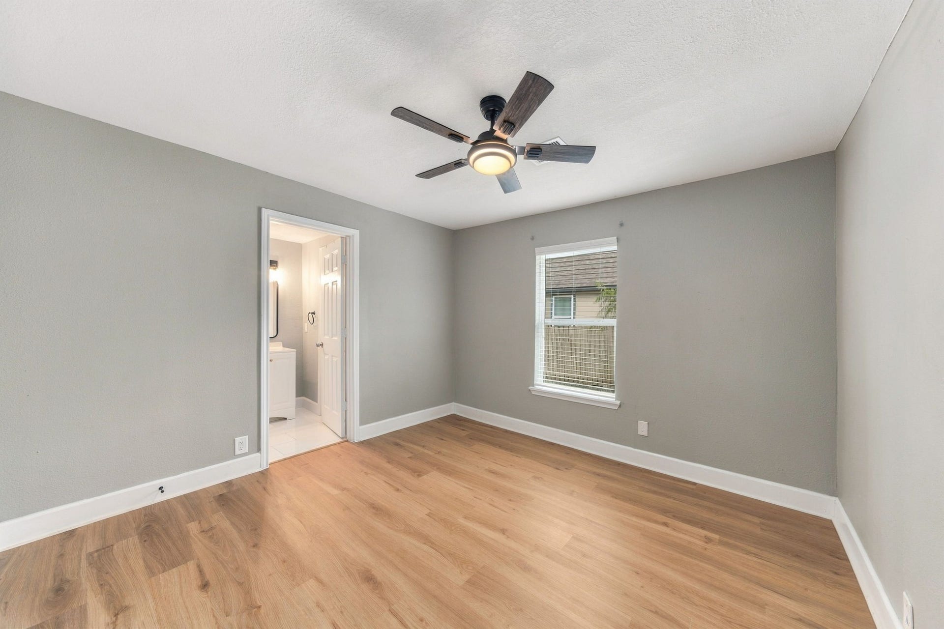 4637 Larkspur Street, Houston, TX 77051 Spacious bedroom featuring fresh neutral paint, sleek hardwood flooring, and a ceiling fan, with an en-suite bathroom for added convenience.