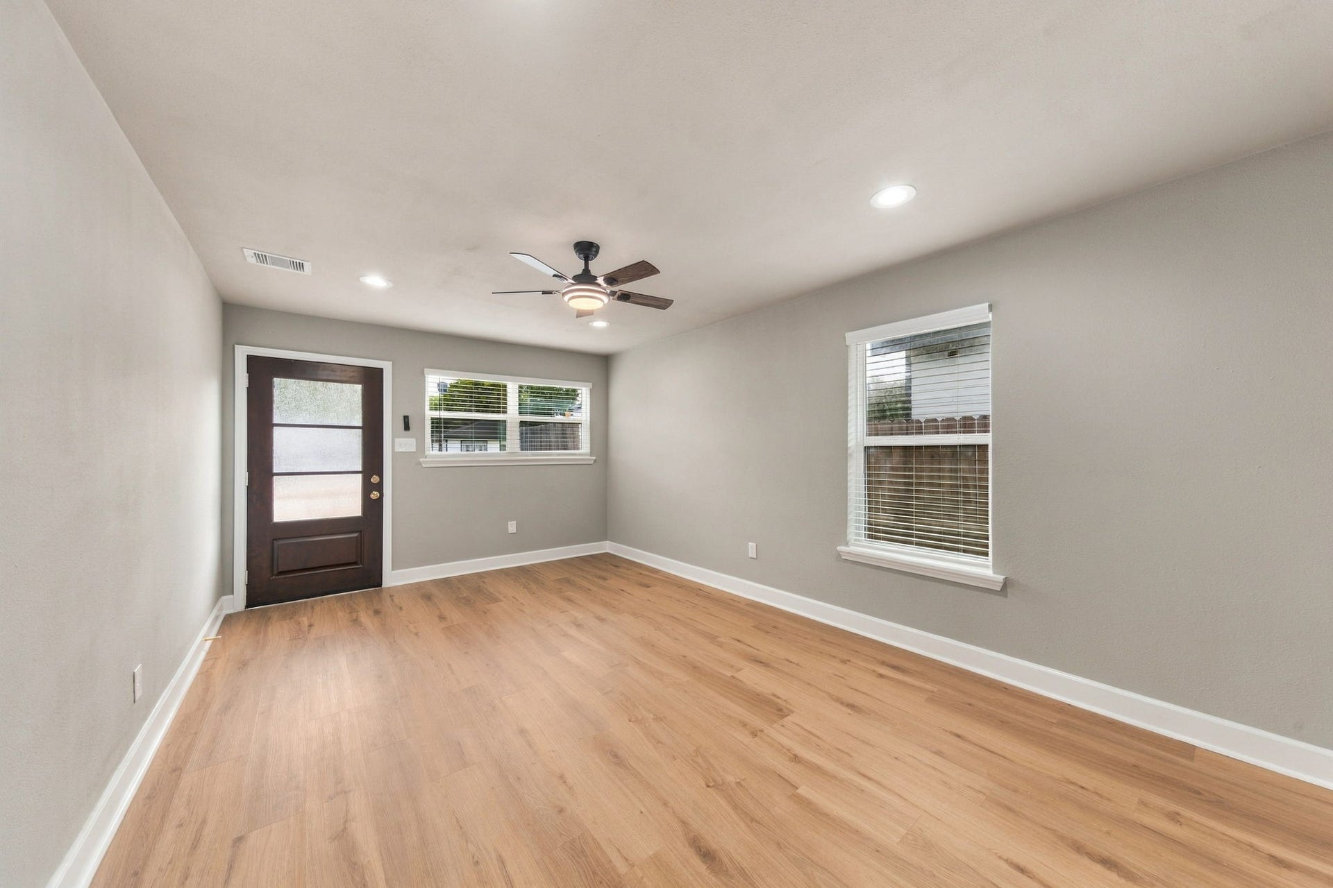 4637 Larkspur Street, Houston, TX 77051 Bright and spacious room featuring sleek hardwood floors, a modern ceiling fan, and ample natural light from two large windows.