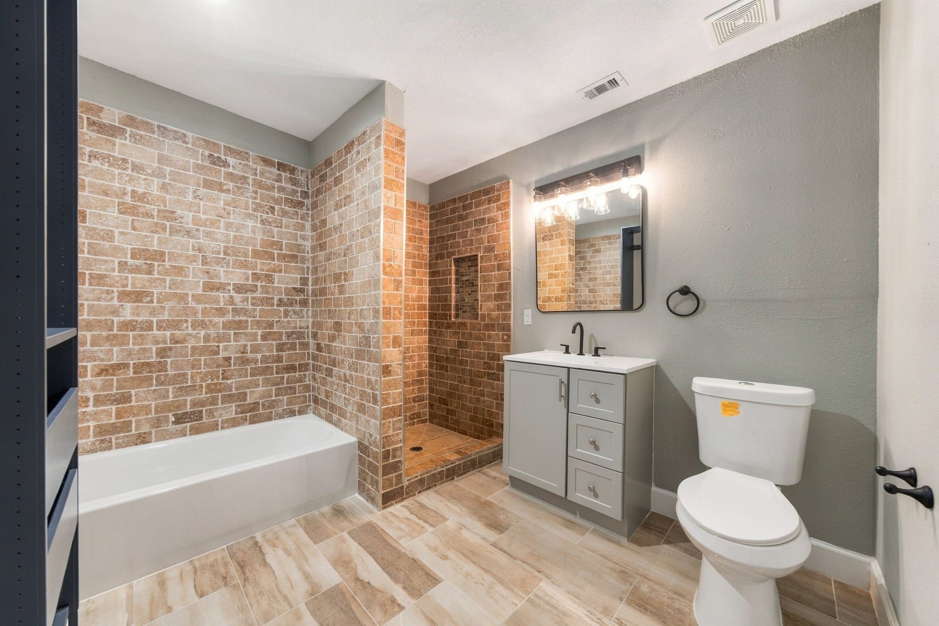 4637 Larkspur Street, Houston, TX 77051 Spacious bathroom featuring a modern vanity, stylish brick tile shower, and a separate bathtub, all complemented by elegant lighting and neutral tones.