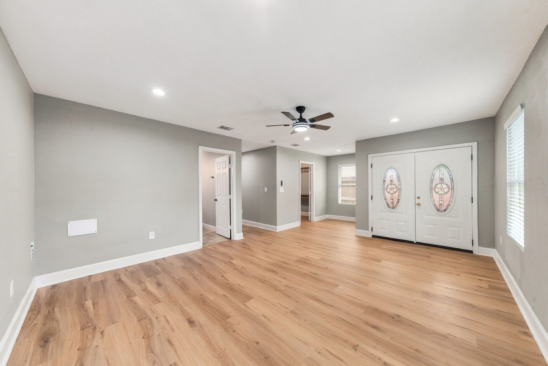 4637 Larkspur Street, Houston, TX 77051 Spacious living area with warm wood flooring, modern ceiling fan, and elegant double doors, offering a welcoming and stylish entrance.