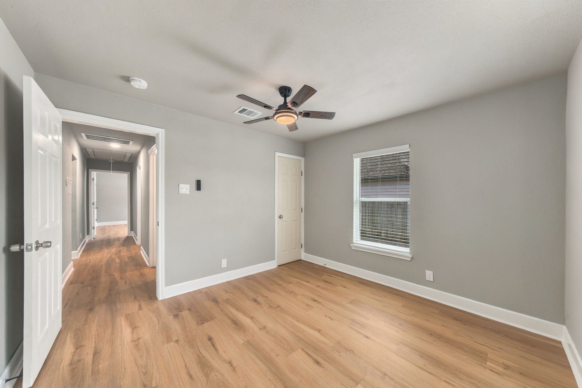 4637 Larkspur Street, Houston, TX 77051 Spacious bedroom with hardwood floors, neutral walls, and a ceiling fan, offering ample natural light through a large window.