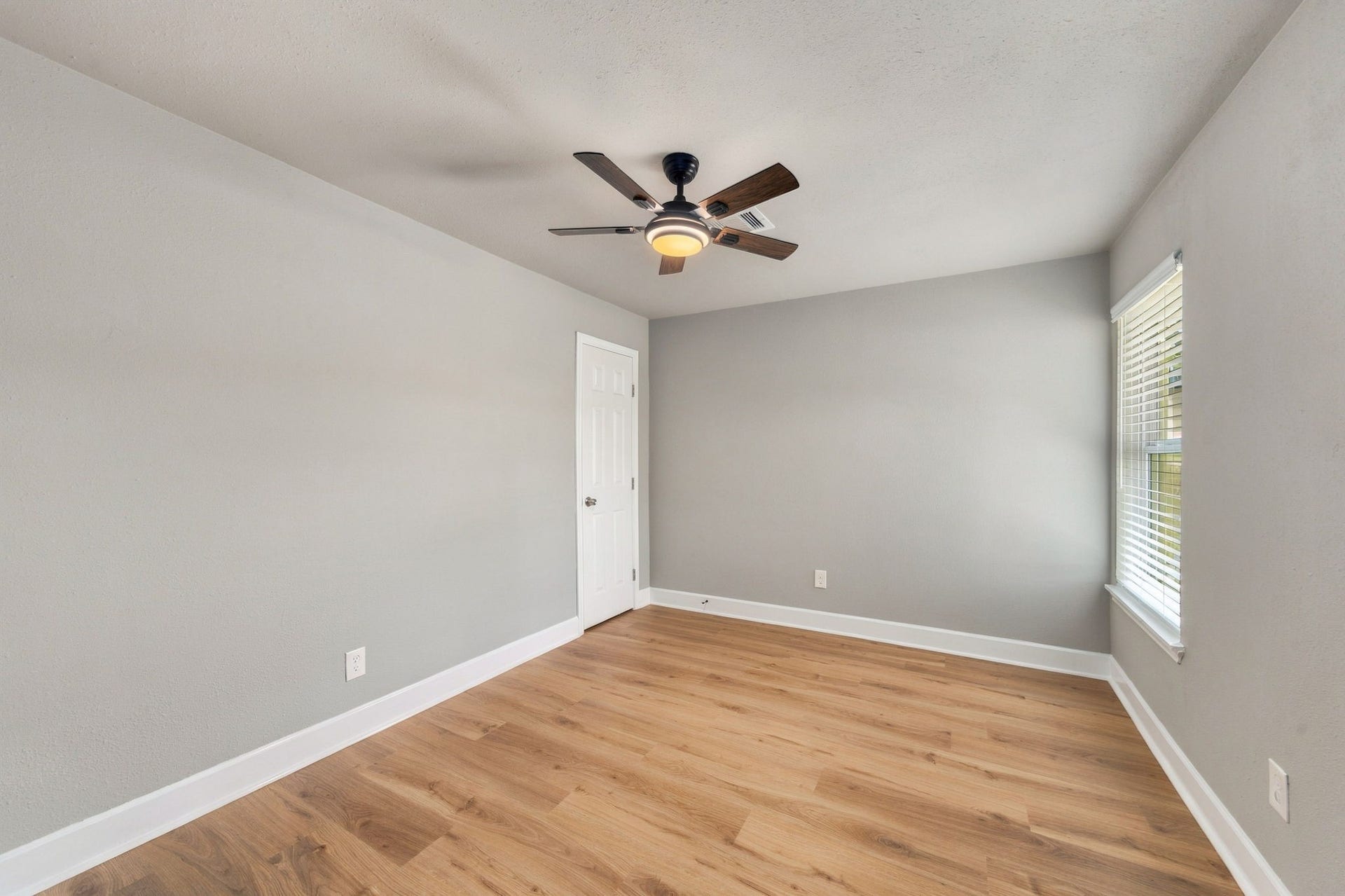 4637 Larkspur Street, Houston, TX 77051 Bright and inviting room featuring sleek hardwood floors, a modern ceiling fan, and abundant natural light through large windows.