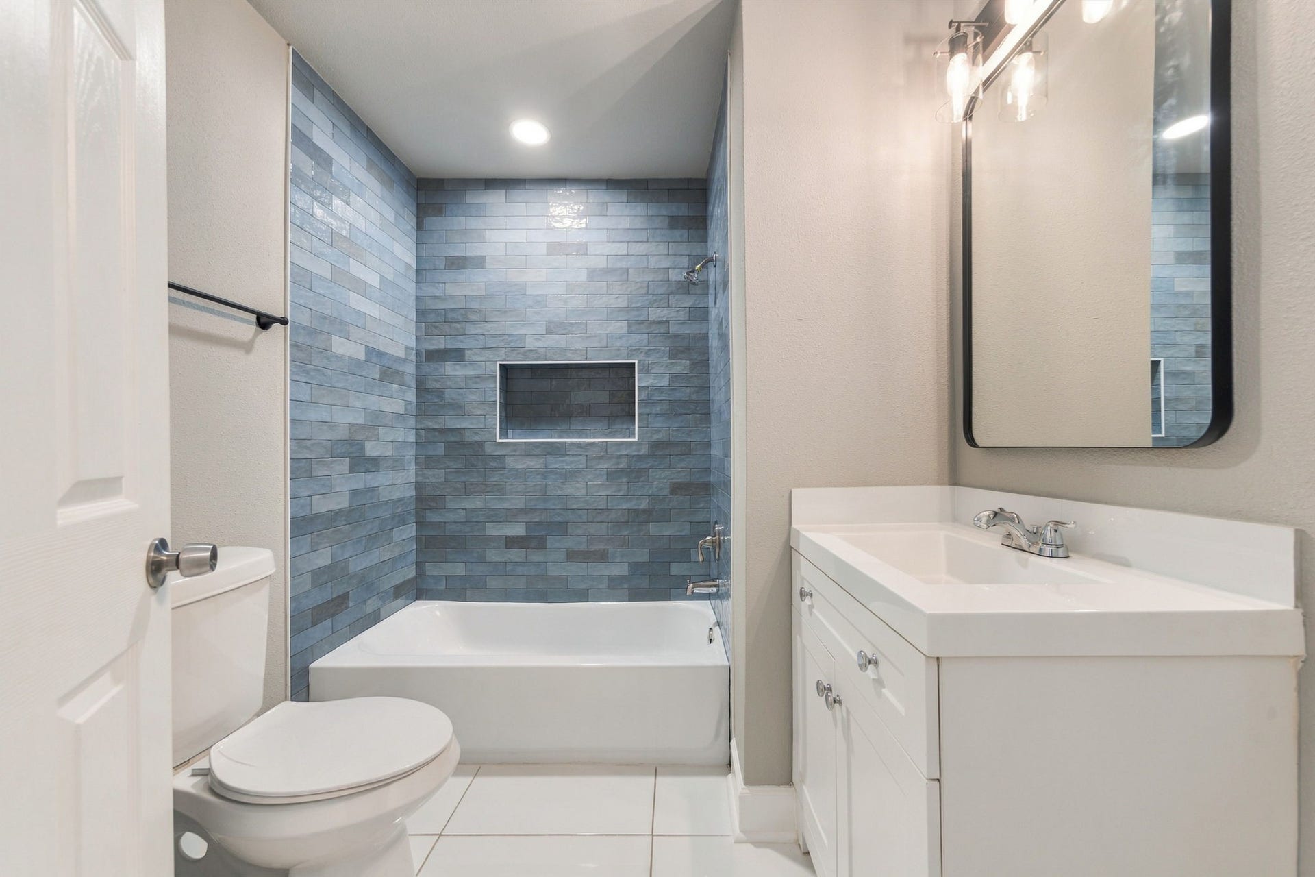 4637 Larkspur Street, Houston, TX 77051 Sleek bathroom featuring a stylish blue tiled shower, modern vanity with ample storage, and elegant lighting.
