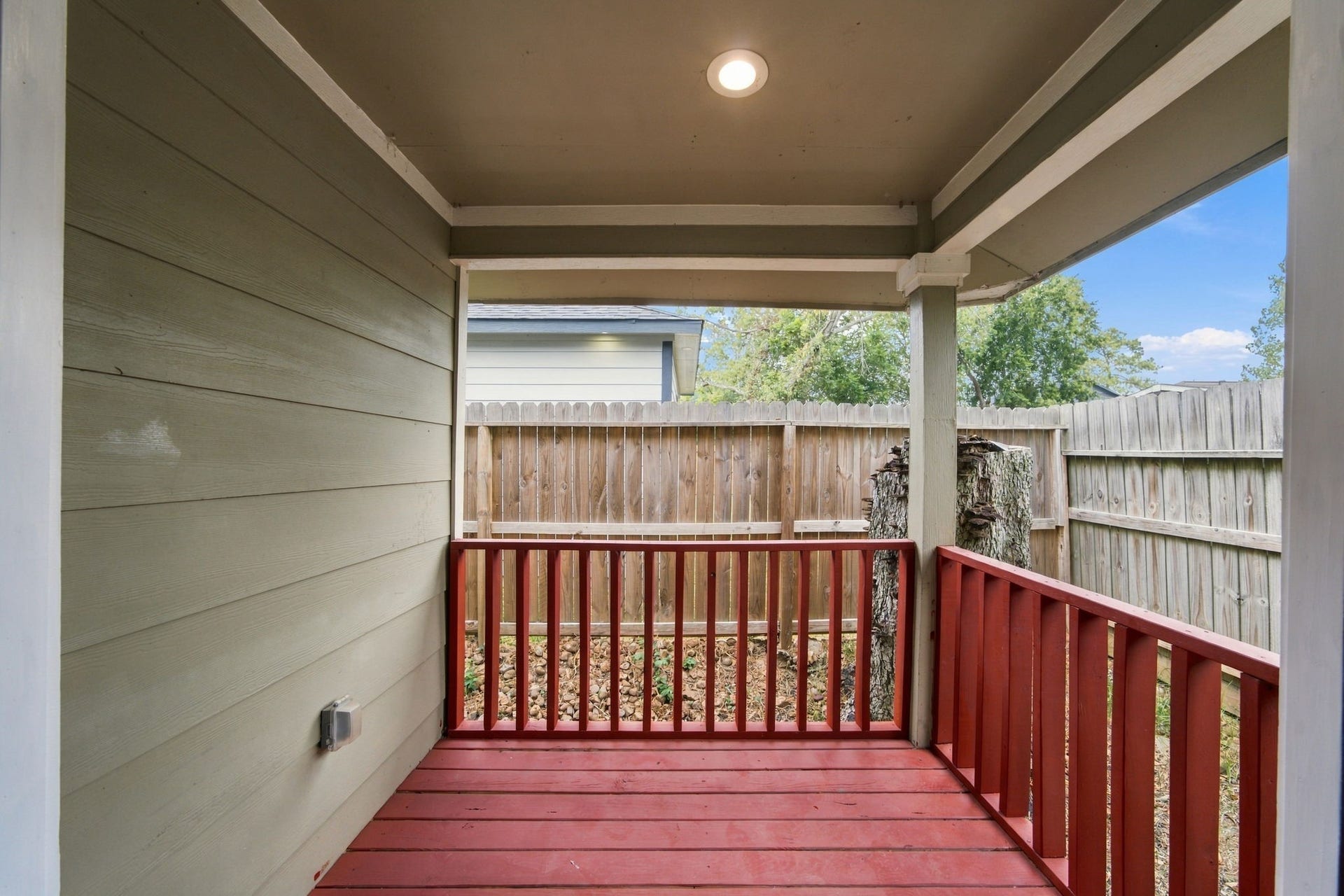 4637 Larkspur Street, Houston, TX 77051 Charming covered patio with vibrant red railing offers a cozy outdoor space, perfect for relaxing and enjoying the fresh air.
