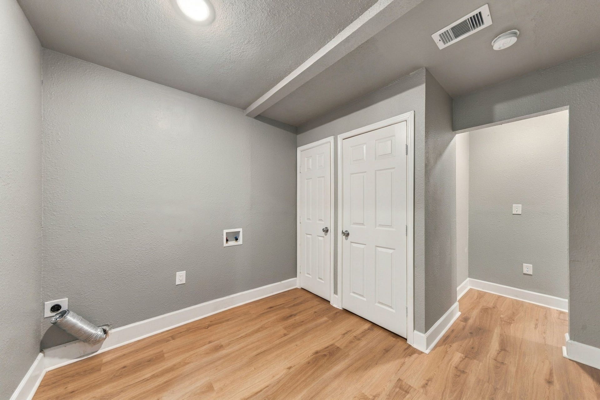 4637 Larkspur Street, Houston, TX 77051 Laundry room with modern gray walls, wood flooring, and ample storage space behind dual doors.