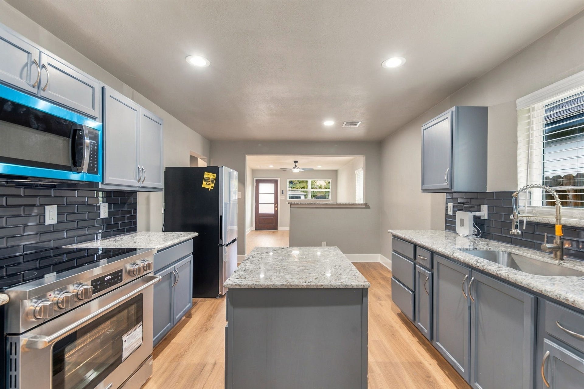 4637 Larkspur Street, Houston, TX 77051 Modern kitchen with sleek stainless steel appliances, granite countertops, and stylish blue cabinetry.