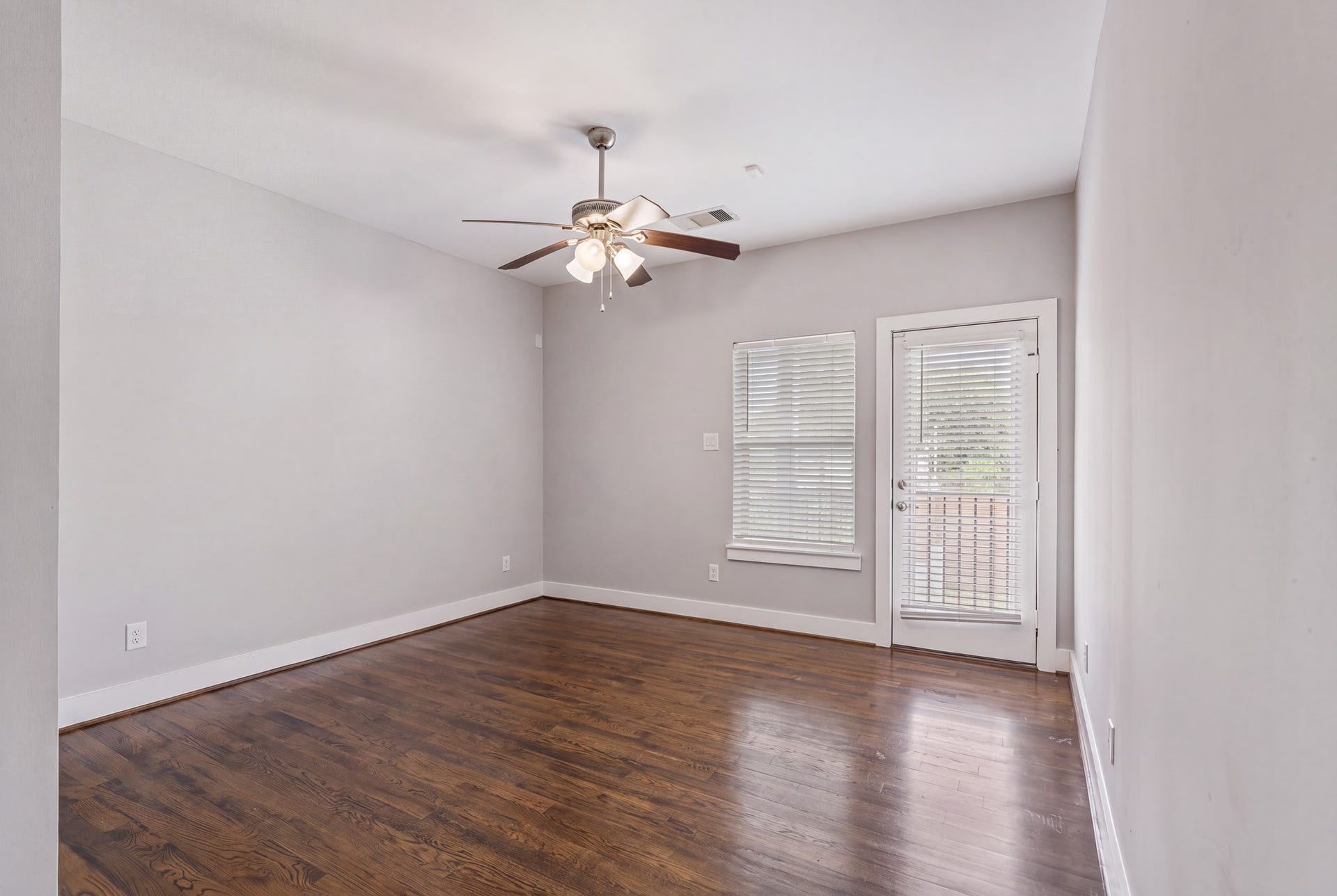 1005 Bingham Street, #5, Houston, TX 77007 Downstairs bedroom featuring hardwood floors and natural light from the window and exterior door.