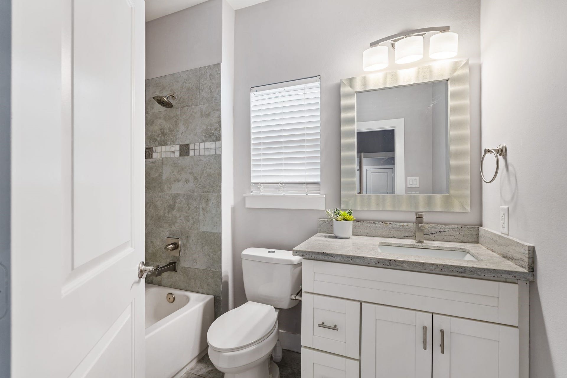 1005 Bingham Street, #5, Houston, TX 77007 Downstairs bathroom with a vanity, updated fixtures, and a tiled tub and shower surround.
