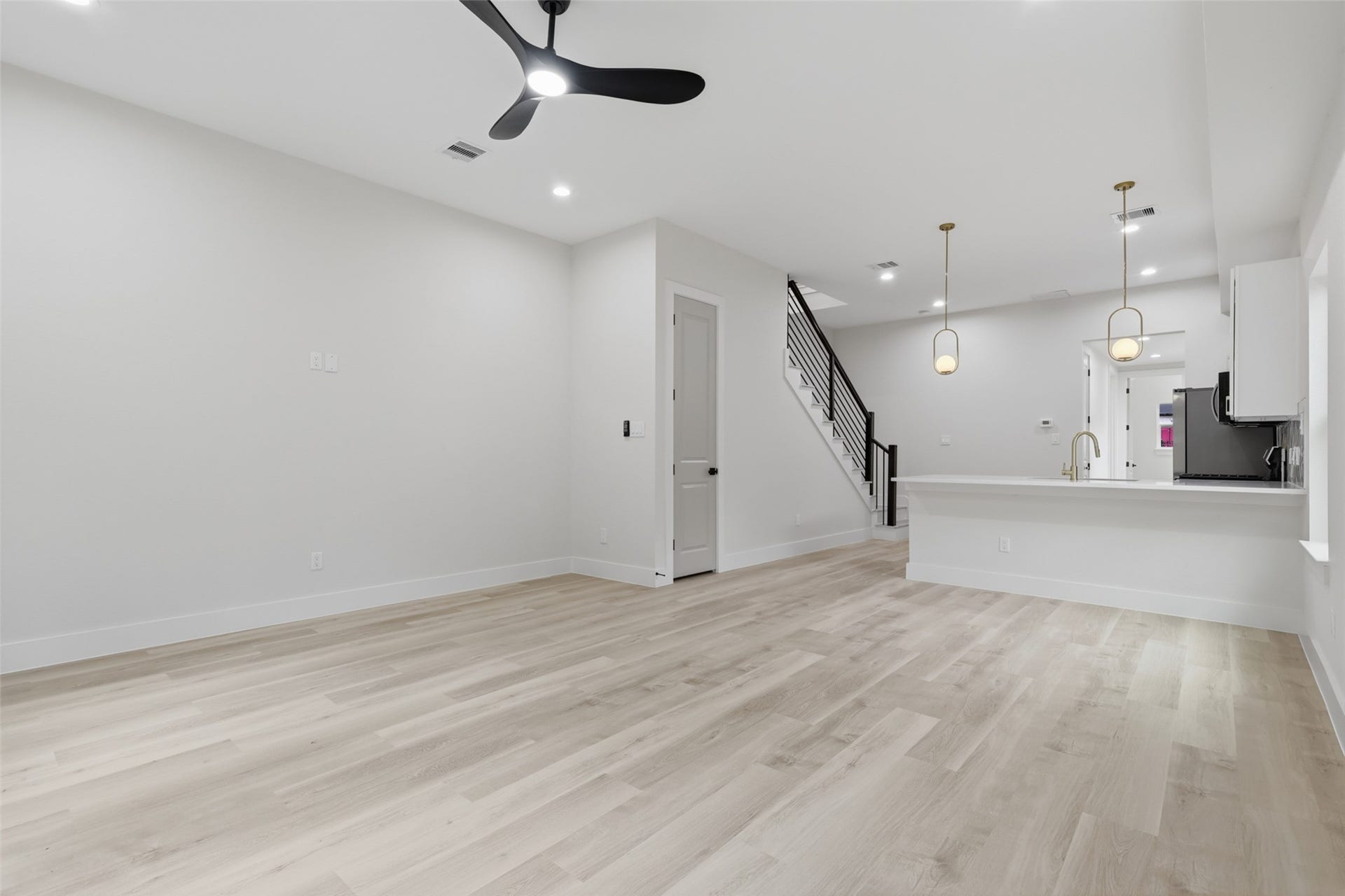 3205 Berry Street, #A/B, Houston, TX 77004 Spacious open-concept living area featuring sleek light LVP flooring, modern ceiling fan, and elegant pendant lighting over a stylish kitchen.