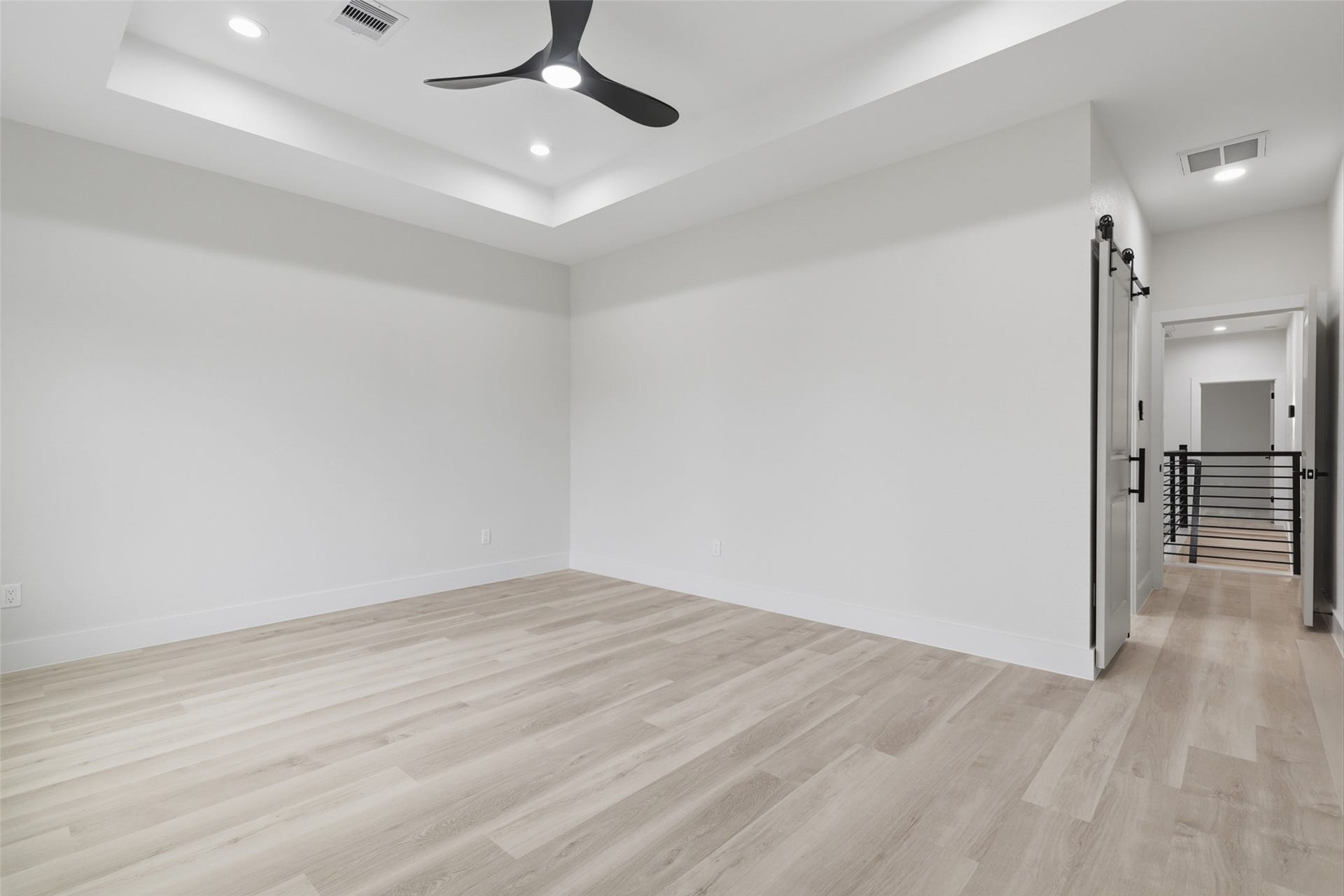 3205 Berry Street, #A/B, Houston, TX 77004 Spacious primary bedroom with sleek light wood LVP flooring, modern recessed lighting, and a stylish ceiling fan, offering a contemporary and airy atmosphere.