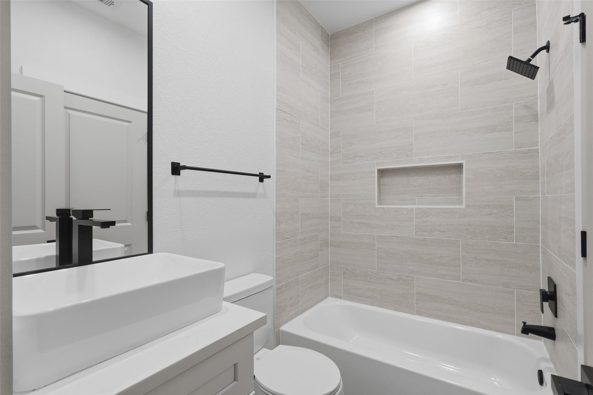 3205 Berry Street, #A/B, Houston, TX 77004 One of the many modern bathroom featuring sleek black fixtures, a spacious vanity with a vessel sink, and a tiled shower with an inset shelf for added convenience.