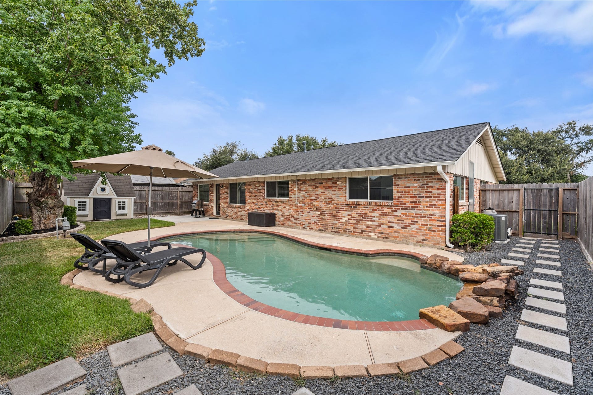 2302 Willowby Drive, Houston, TX 77008 Private backyard retreat featuring a sparkling pool surrounded by lush greenery - perfect for relaxation and entertaining on hot Houston days.