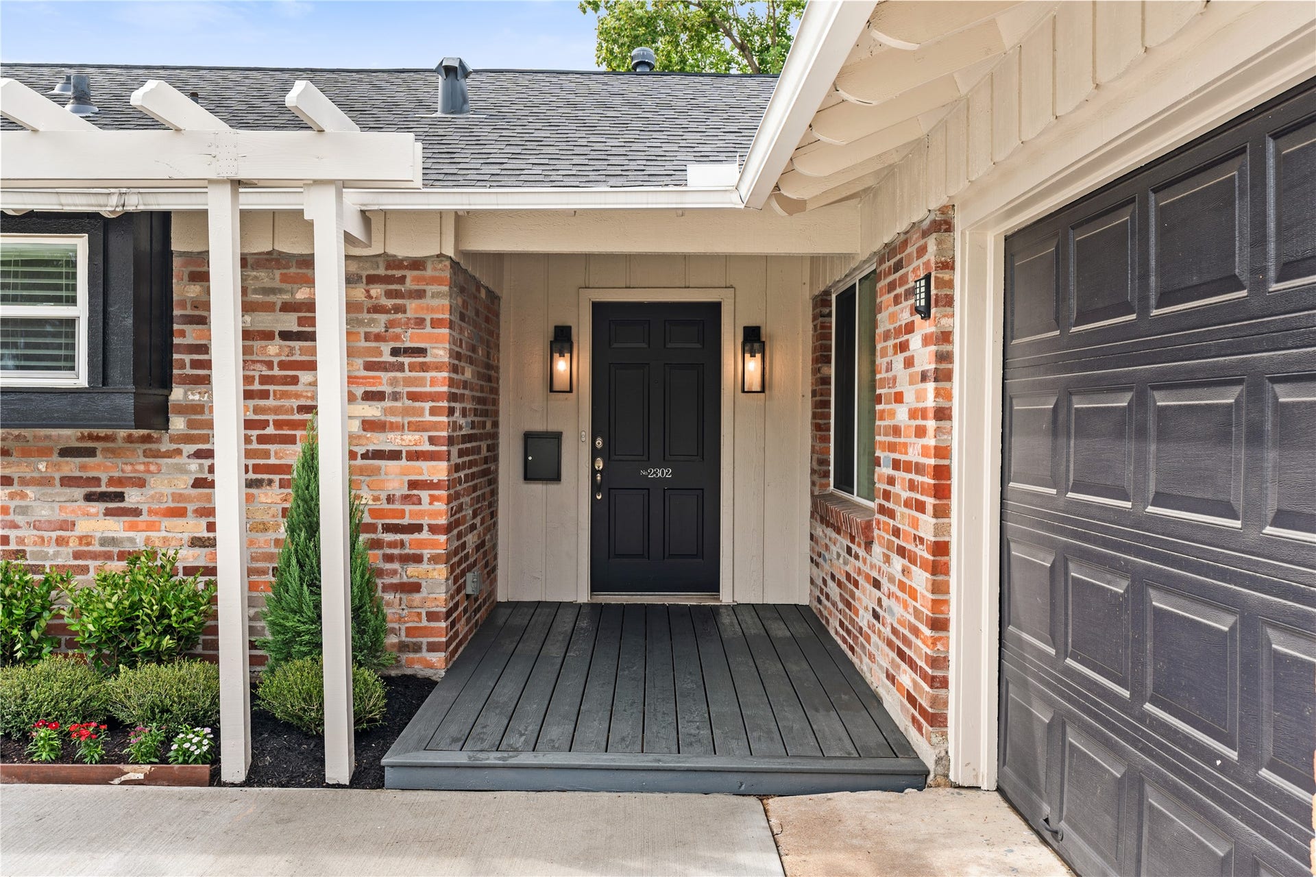 2302 Willowby Drive, Houston, TX 77008 Charming entryway with a classic black door, flanked by stylish lanterns and set against a warm brick facade, offering a welcoming first impression.