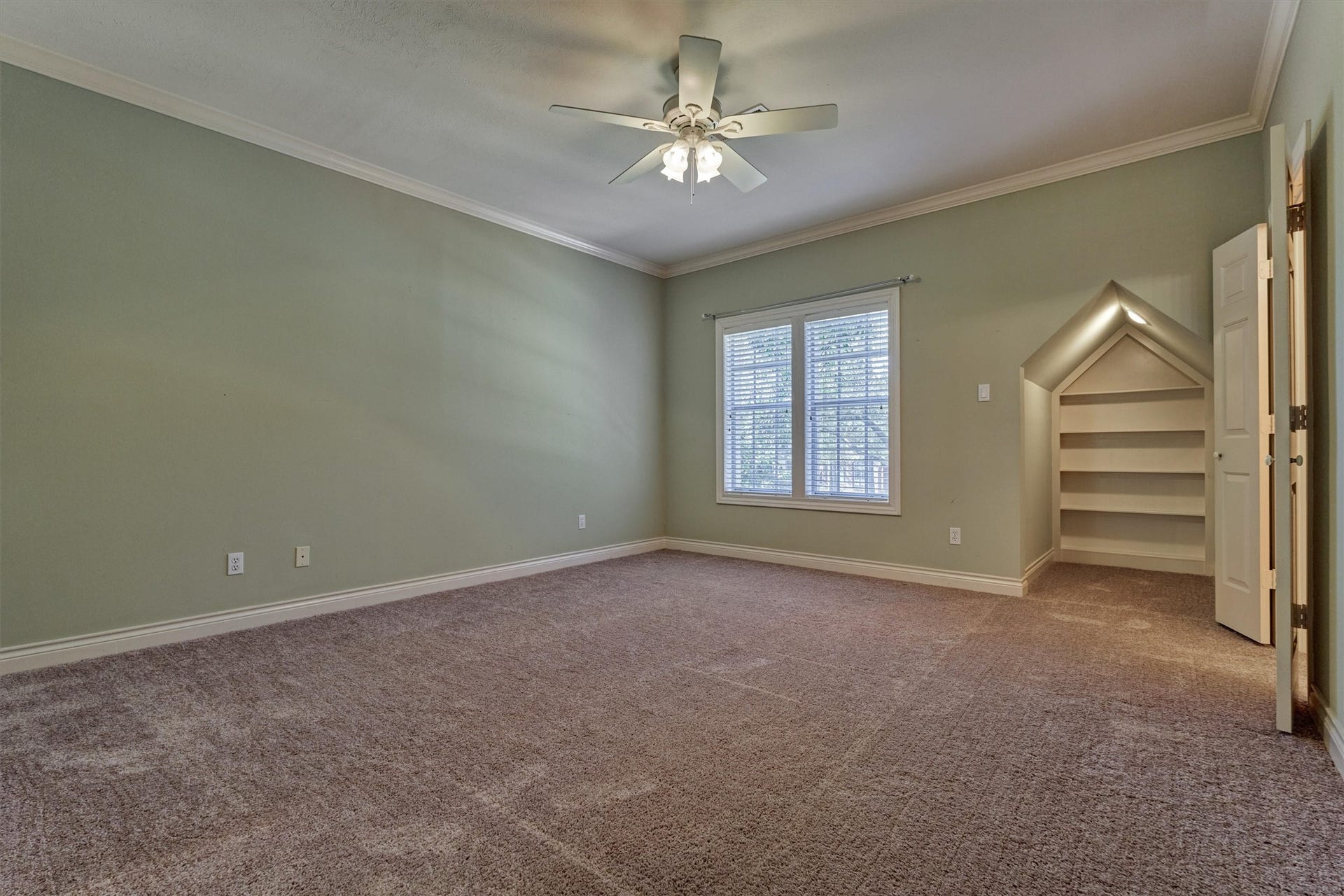 26 S Brokenfern Drive, The Woodlands, TX 77380 This spacious upstairs secondary bedroom has crown molding, a ceiling fan with lights, and plush carpet. A built-in, house-shaped shelving niche with a peaked, lighted opening adds a charming storage or display feature. A large window brings in natural light, and the large walk-in closet offers plenty of room. The bedroom shares a bath with another secondary bedroom.