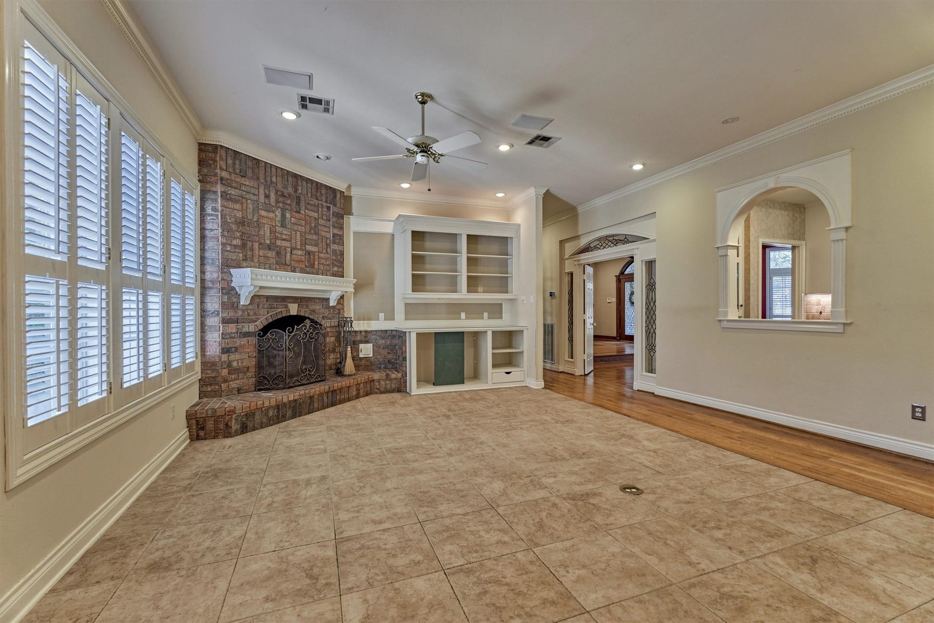 26 S Brokenfern Drive, The Woodlands, TX 77380 Gather around the gas log fireplace in this downstairs family room, open to the kitchen through an arched pass-through. Large shuttered windows overlook the backyard and fill the room with light. Built-in shelves and cabinets give you room for a TV, books, and dcor, and the mix of tile and hardwood floors is easy to live in.