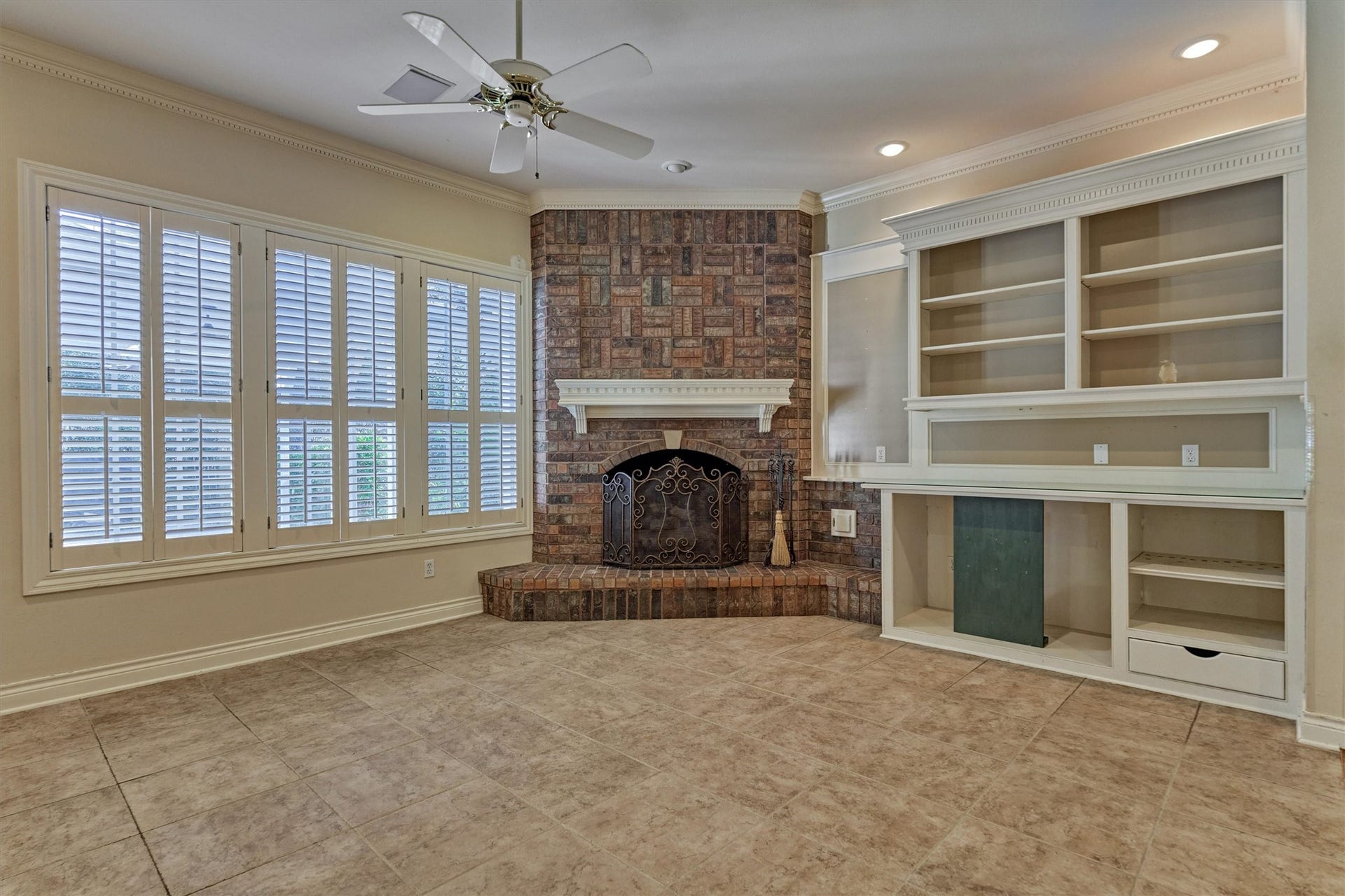 26 S Brokenfern Drive, The Woodlands, TX 77380 Gather around the gas log fireplace in this downstairs family room, open to the kitchen through an arched pass-through. Large shuttered windows overlook the backyard and fill the room with light. Built-in shelves and cabinets give you room for a TV, books, and dcor, and the mix of tile and hardwood floors is easy to live in.